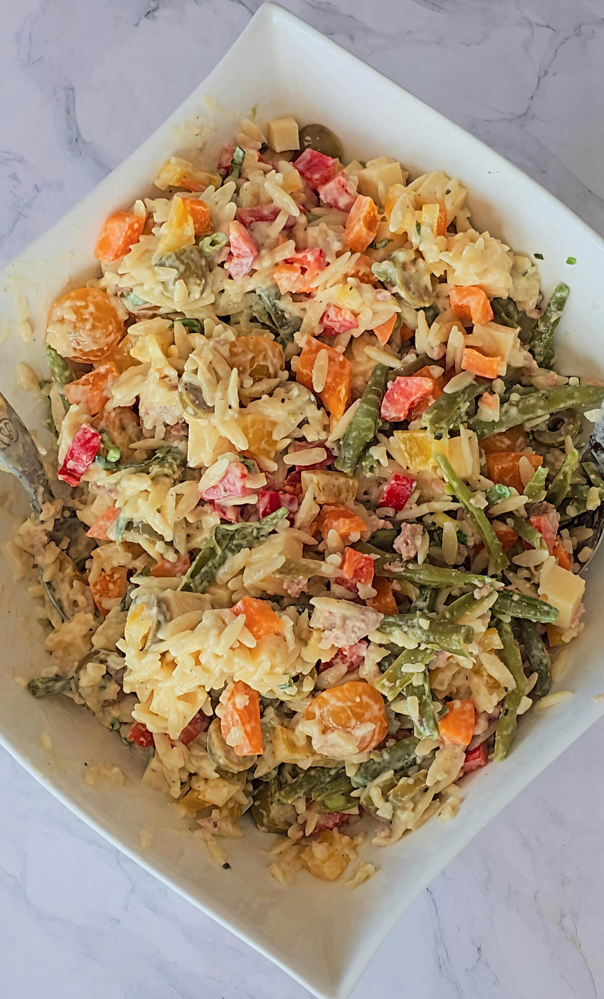 Une salade d'orzo méditerranéenne dans un plat blanc.