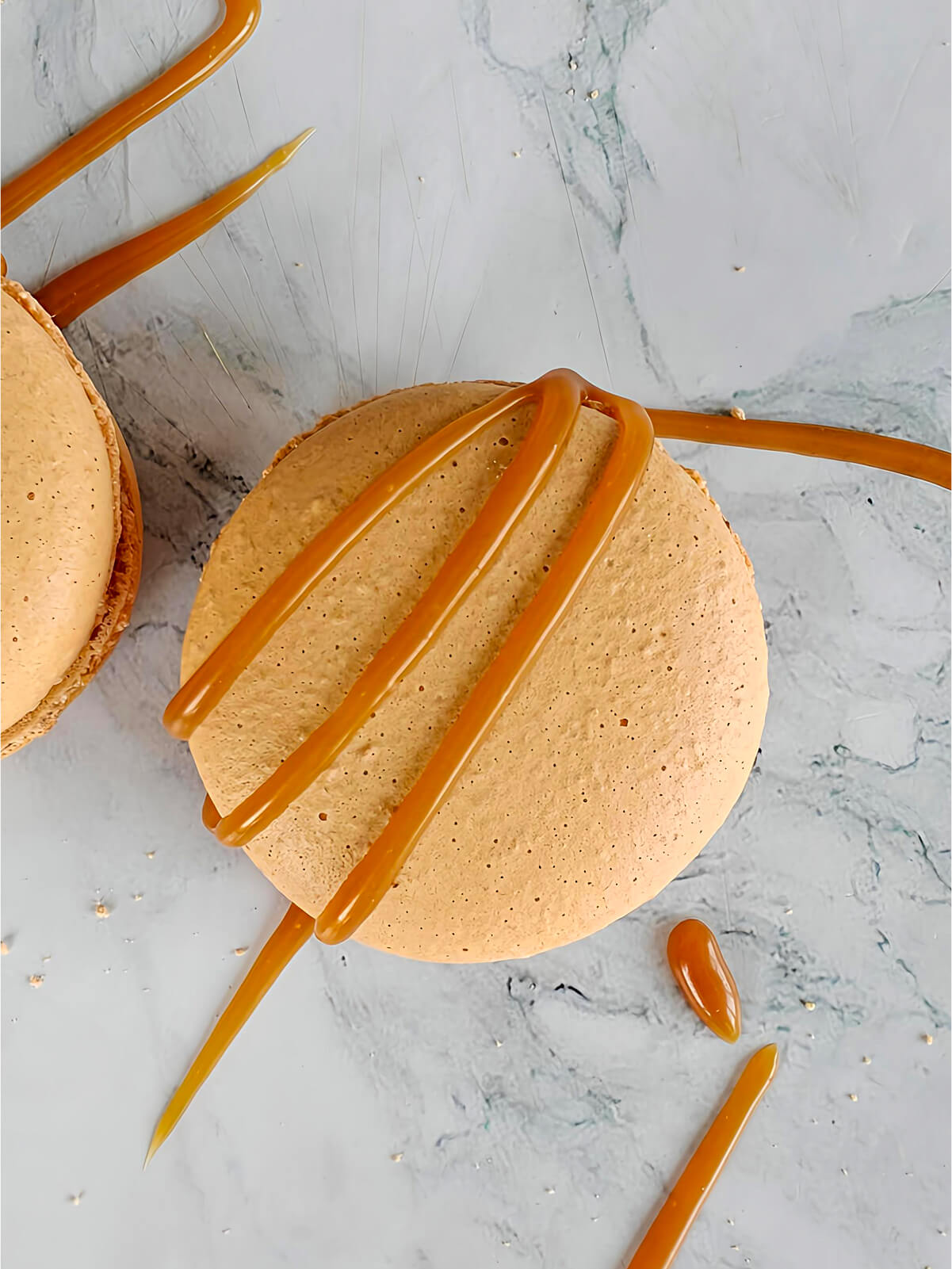 Des macarons caramel beurre salé sur un fond blanc marbré.