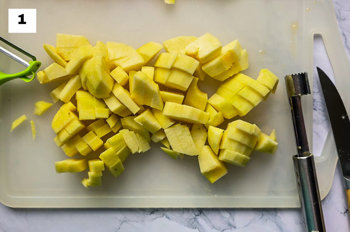 Des pommes coupées en petits dés sur une planche à découper blanche.
