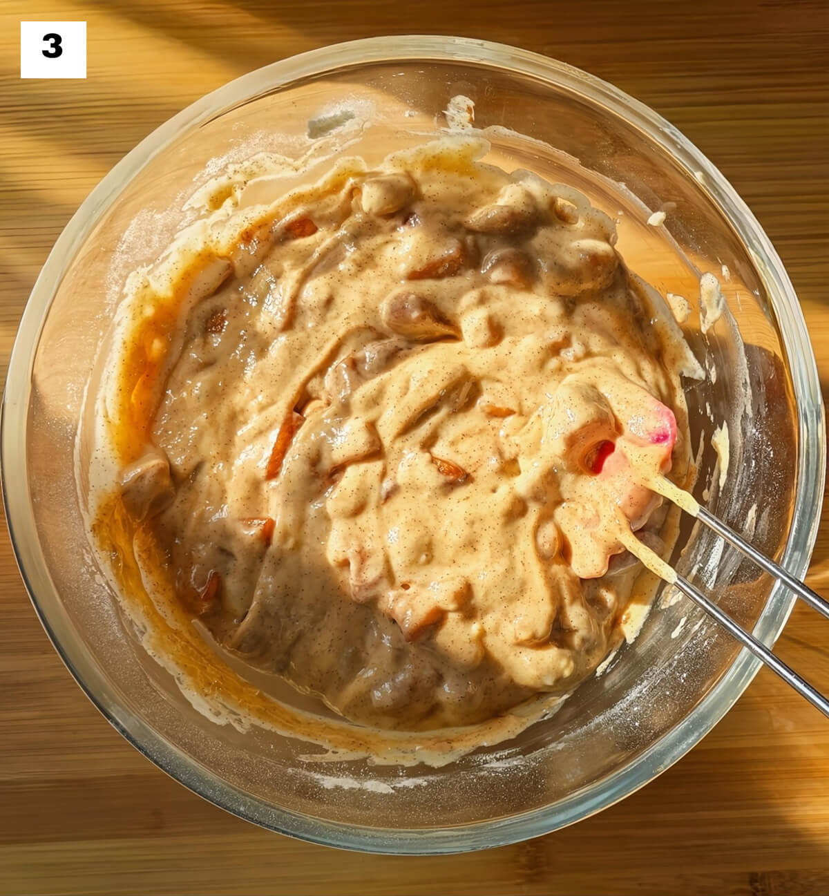 Une pâte à muffins dans un saladier en verre, avec une spatule, sur un fond en bois.