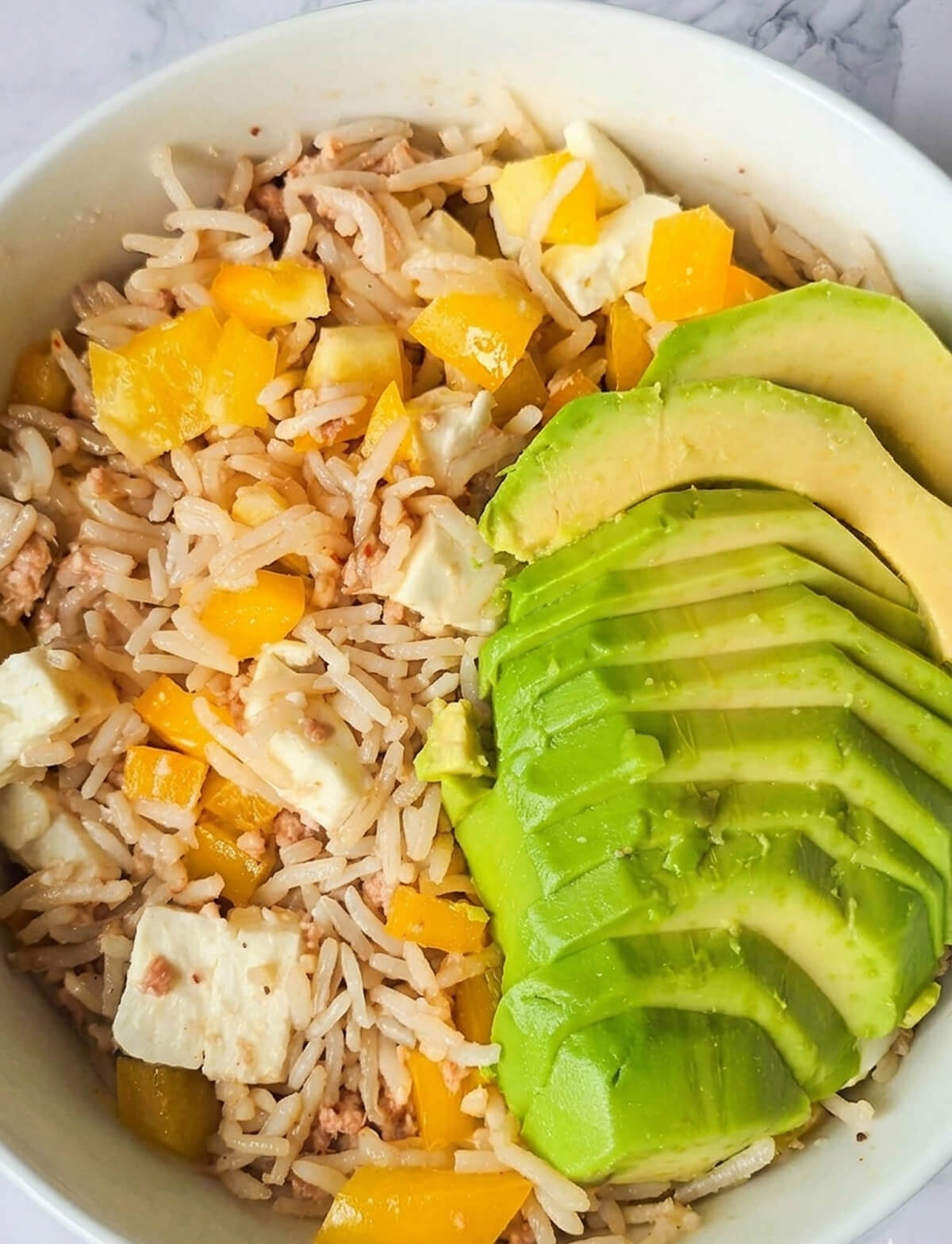 Une salade de riz au thon froide pour l'été, dans un bol blanc.