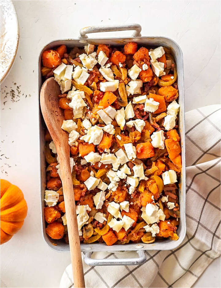 Un gratin de patates douces dans un plat, avec un cuillère en bois, torchon en dessous du plat.