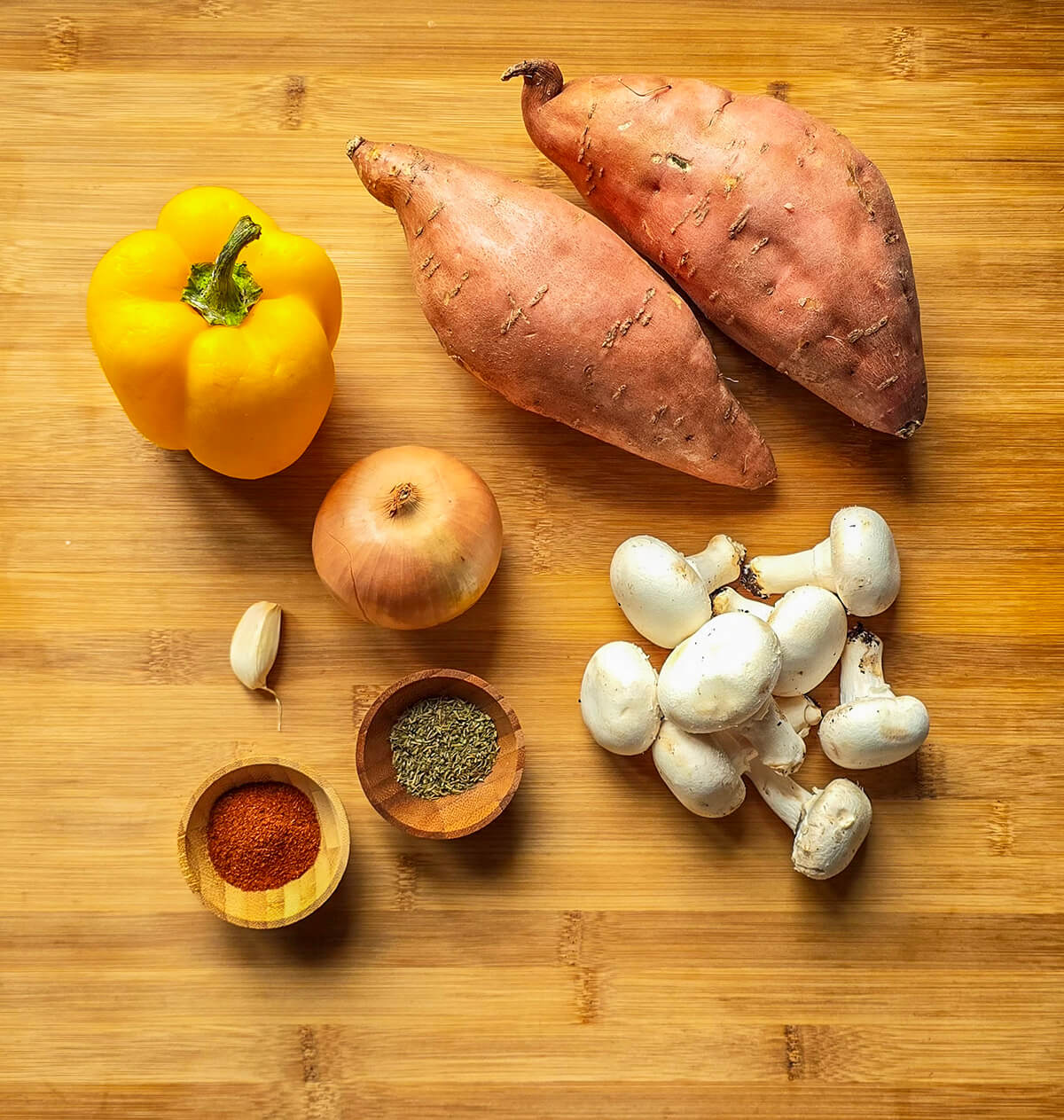 Des ingrédients pour faire un gratin de patates douces, sur une planche en bois.