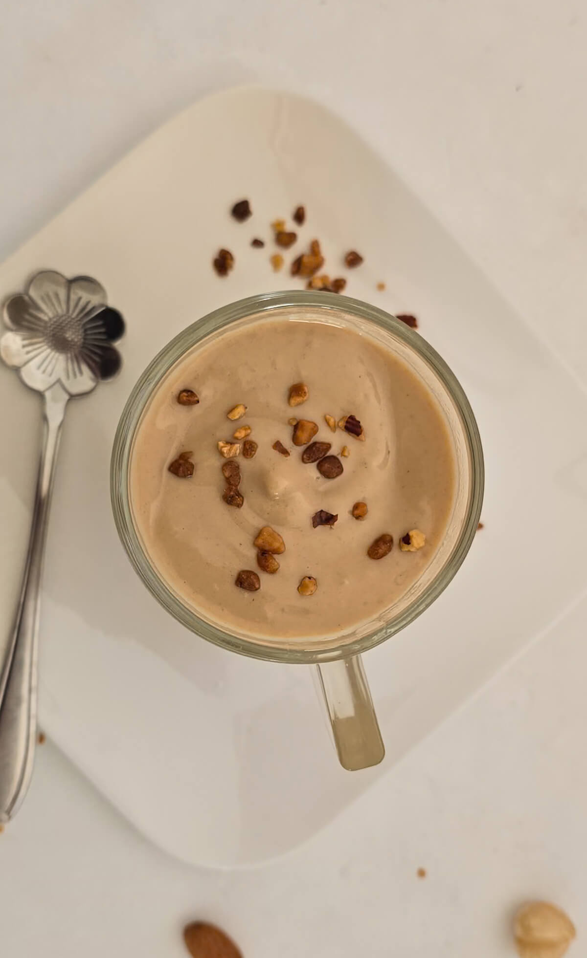 Une crème dessert dans une verrine avec une cuillère, dans une petite assiette blanche.