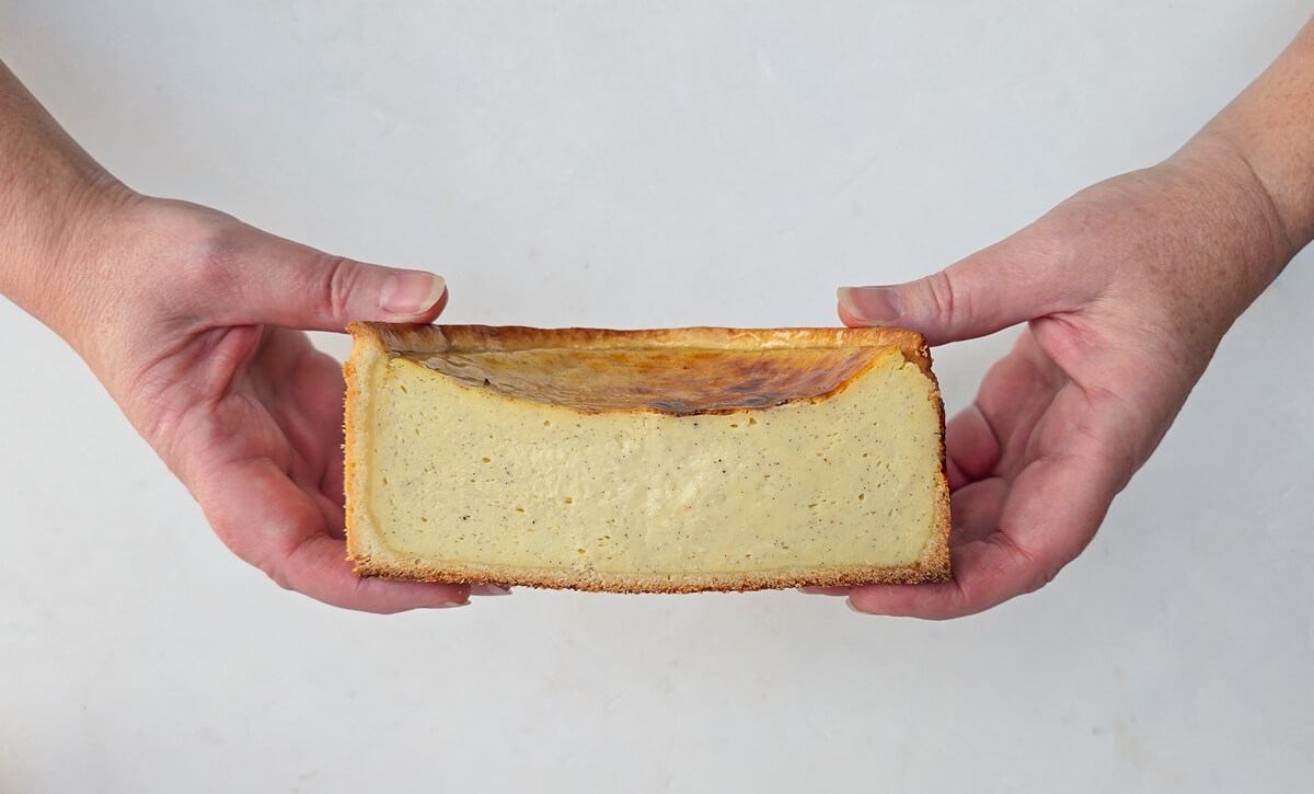 deux mains tenant une moitié de flan vanille. 