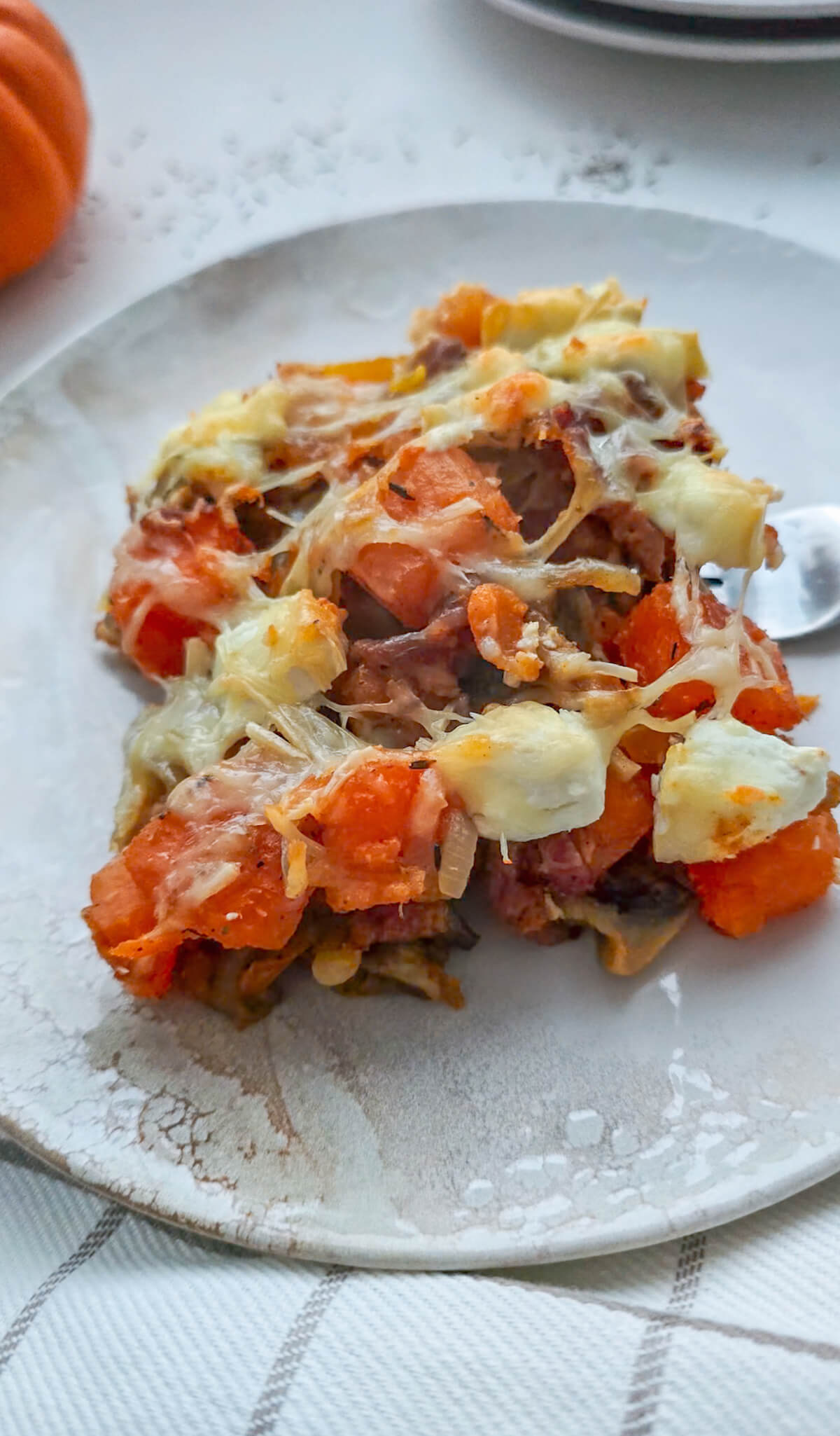 Une part de gratin patates douces dans une assiette blanche.