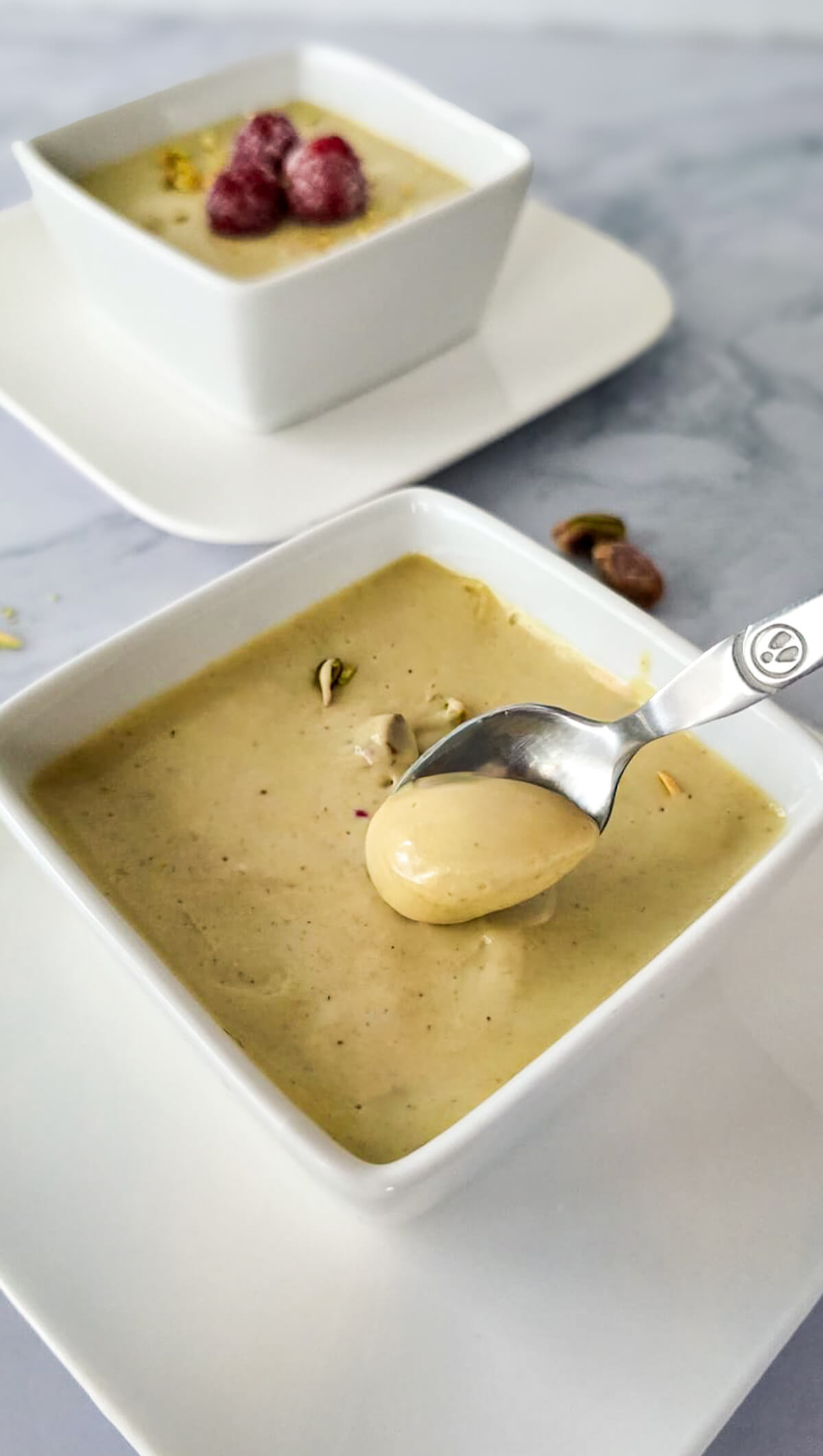 Un dessert à la pistache dans une verrine blanche.