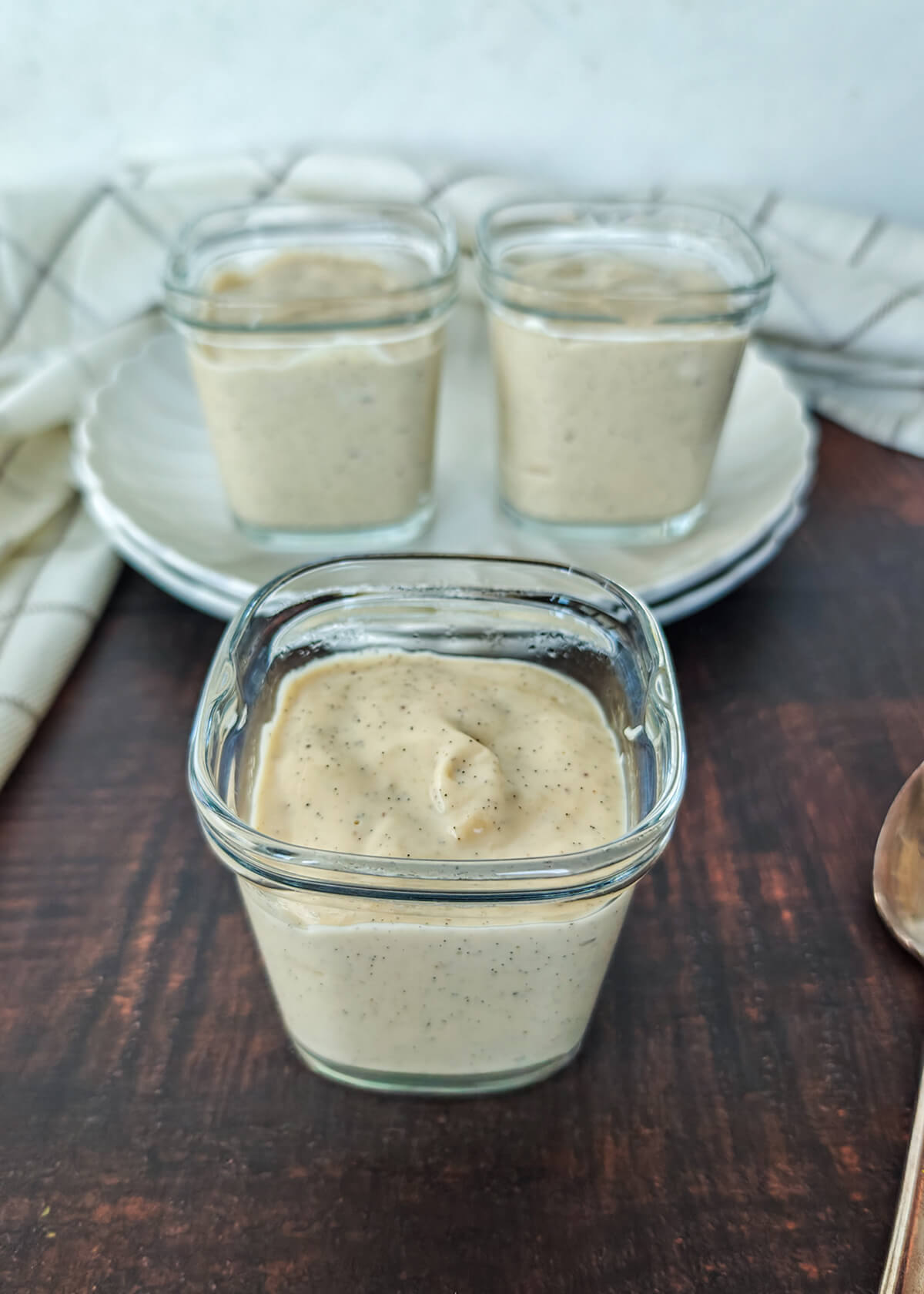 des crèmes dessert vanille dans leurs pots yaourtière Seb, sur un fond de bois.