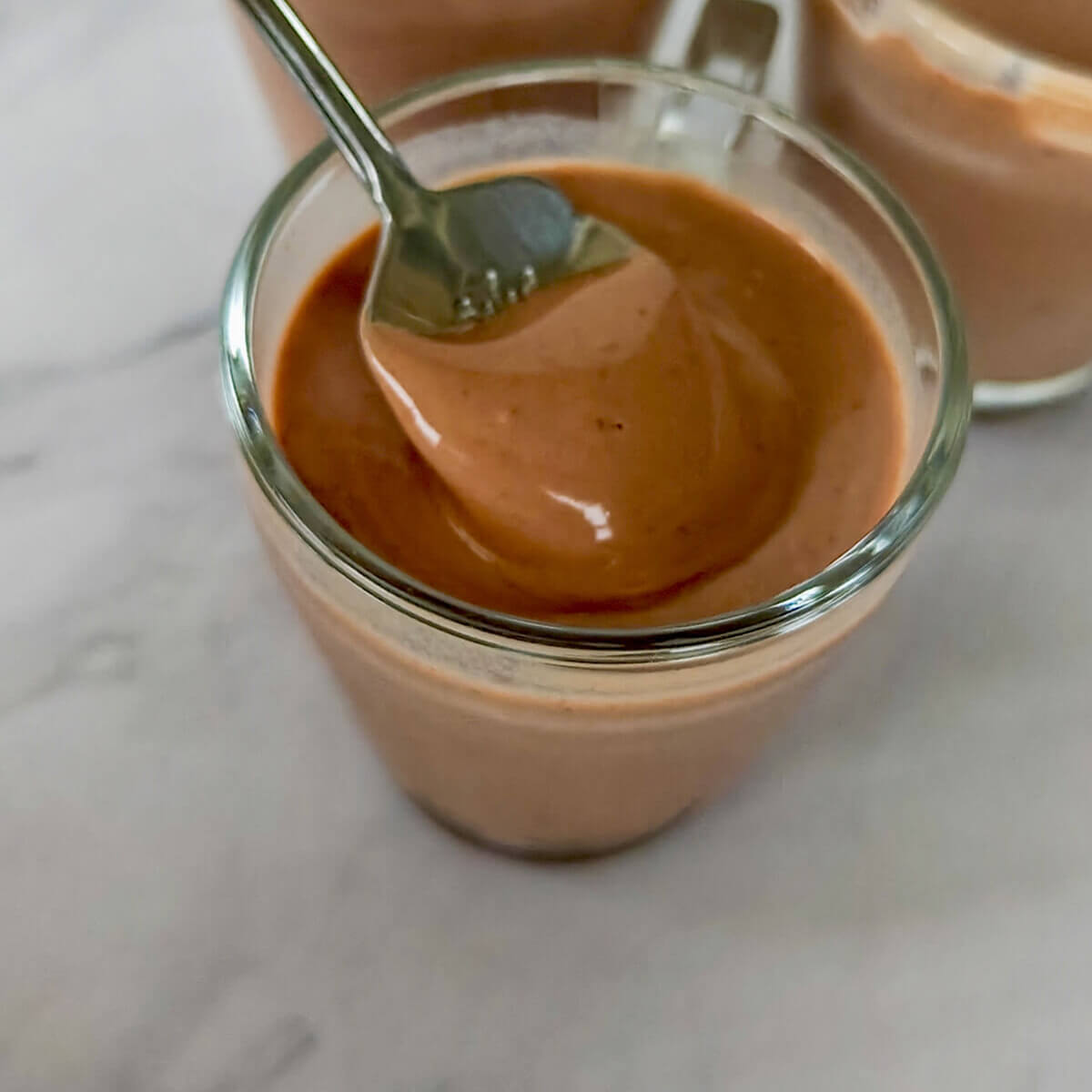 Une cuillère tenant une crème dessert chocolat sans œufs, facile et rapide à réaliser.