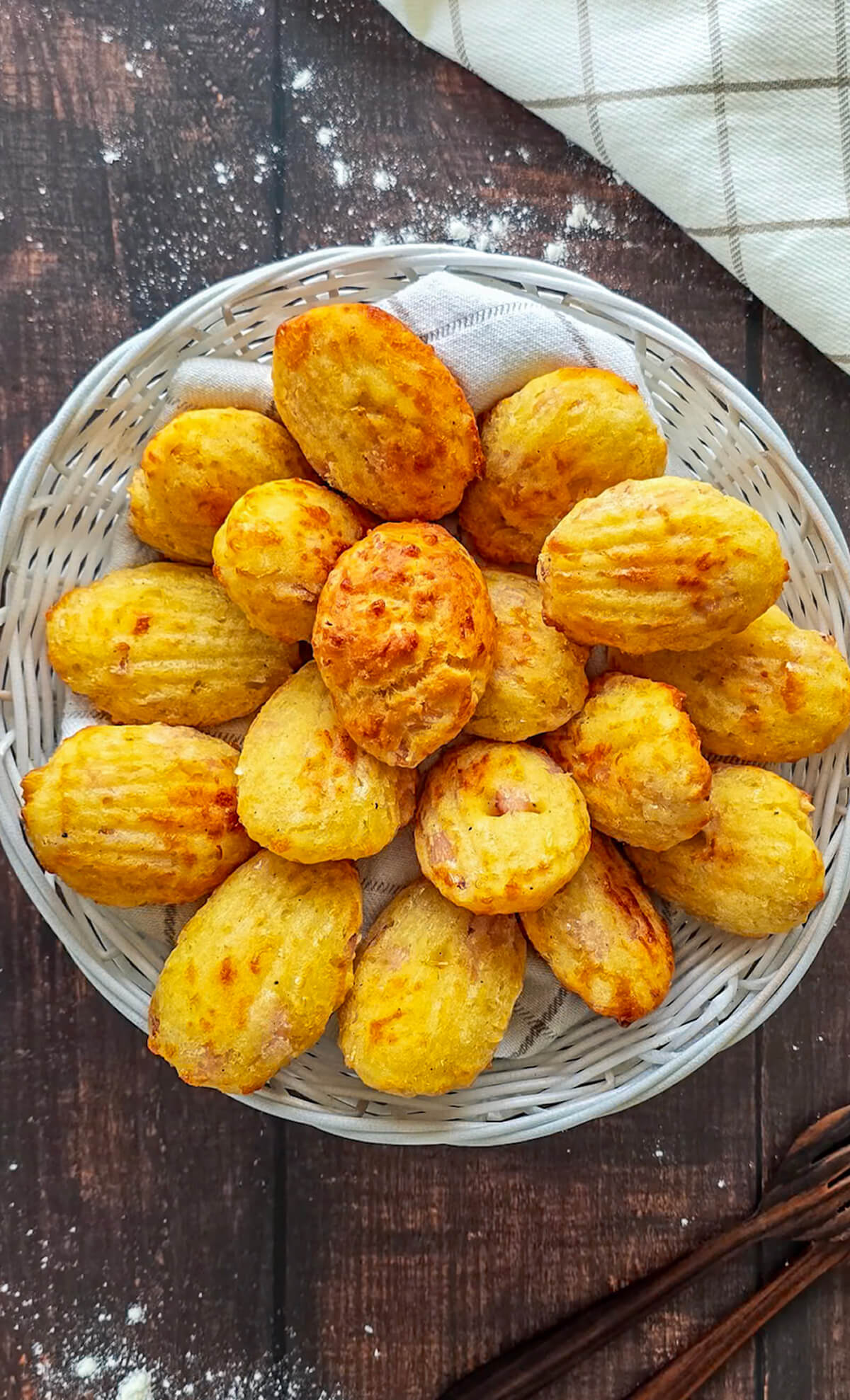 Des madeleines salées au bacon comté dans un plat rond, sur un fond en bois.