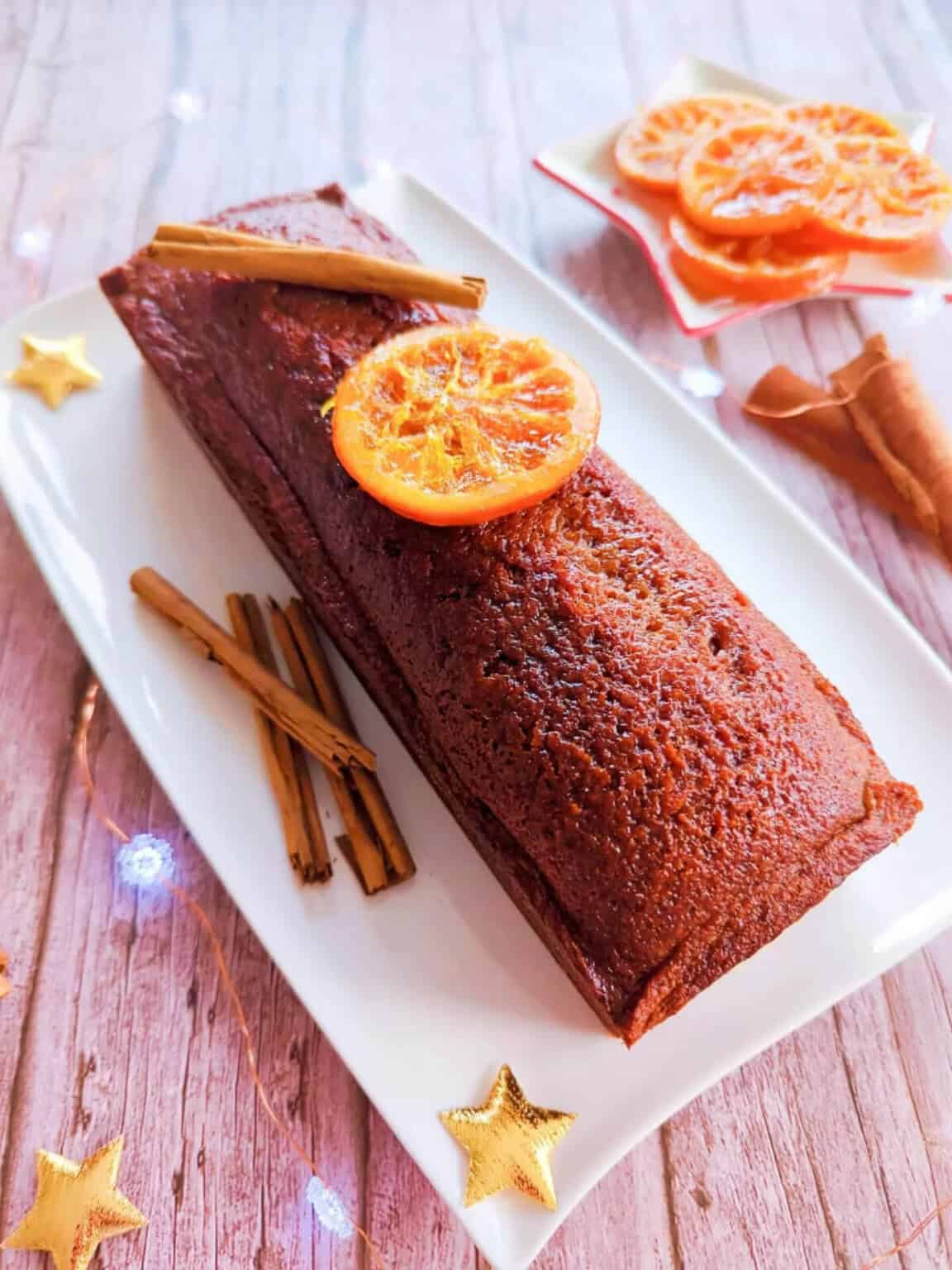 A traditional gingerbread on a white plate, on a wooden background, with stars and lights.
