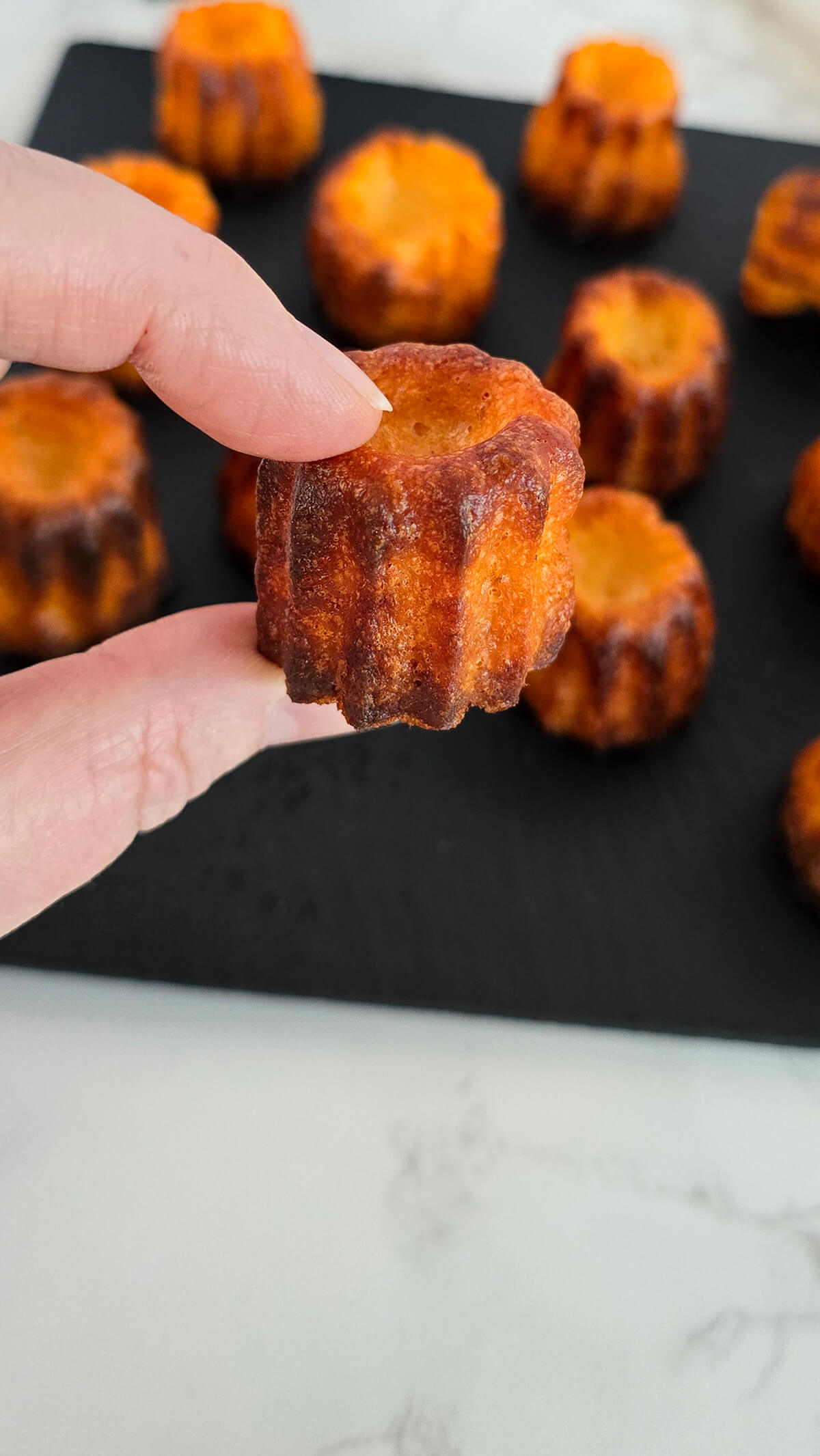 Une main tenant un cannelé salé.