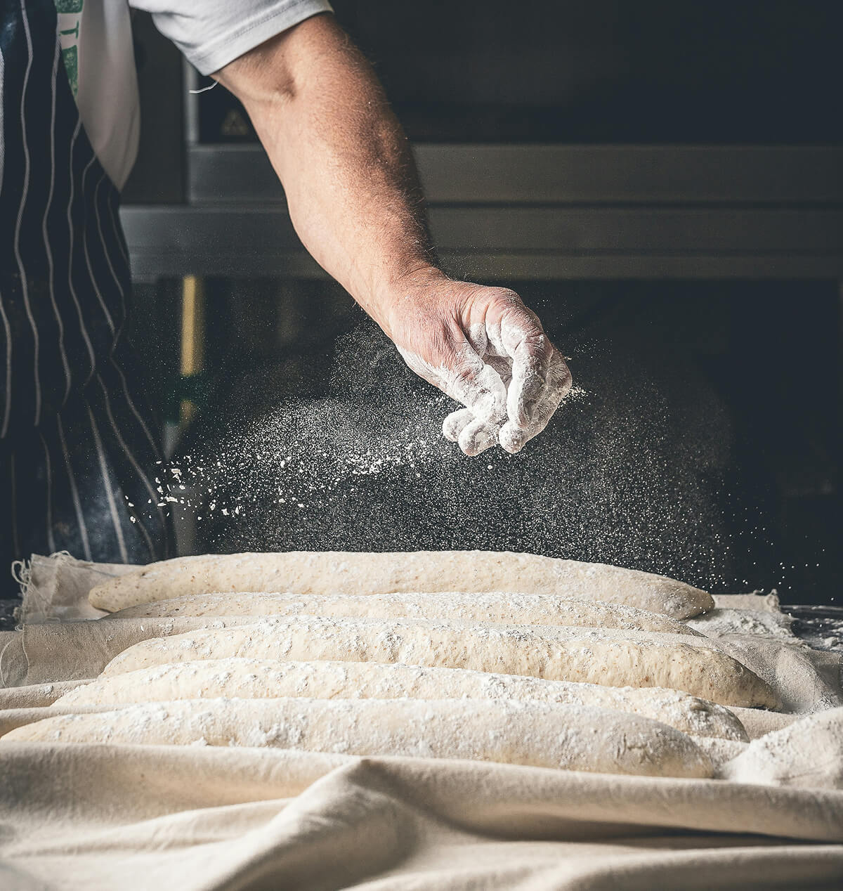 Une main qui saupoudre de la farine sur du pain.