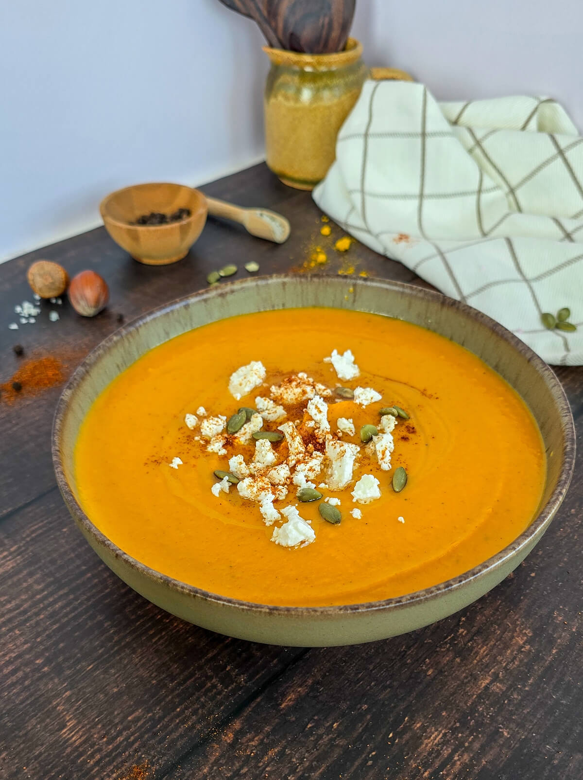 Un velouté de butternut dans un bol marron, sur une surface marron.