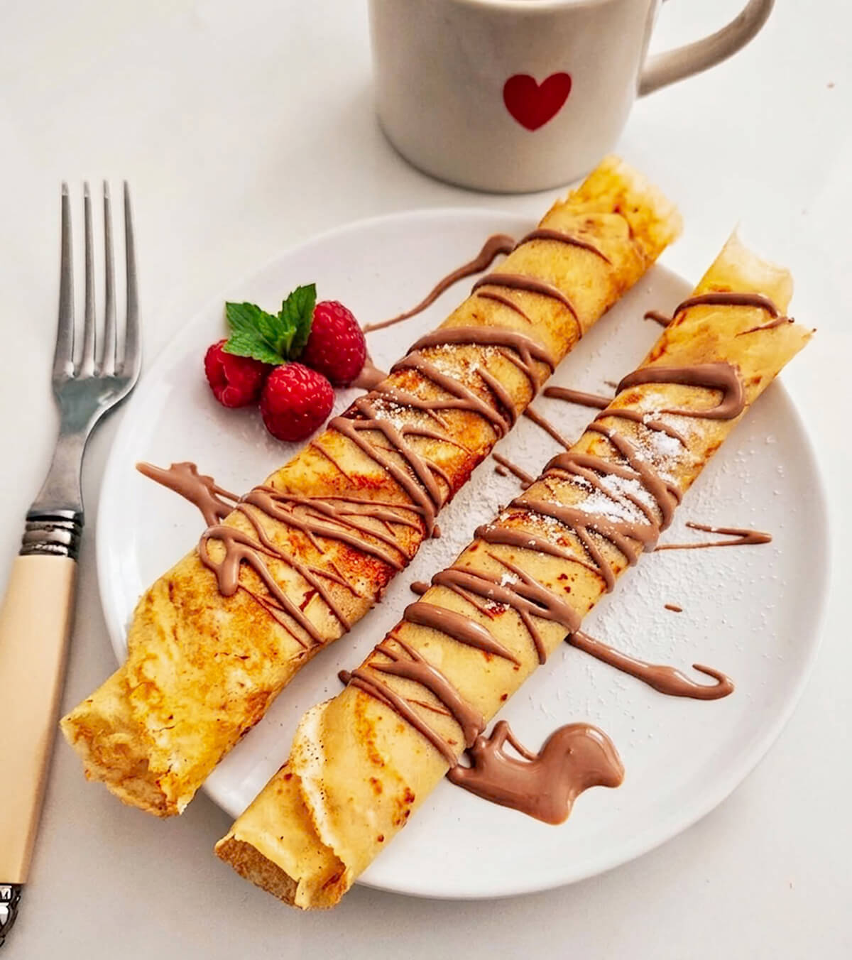 Des crêpes avec un filet de pâte à tartiner dans une assiette, idéal pour la Chandeleur.