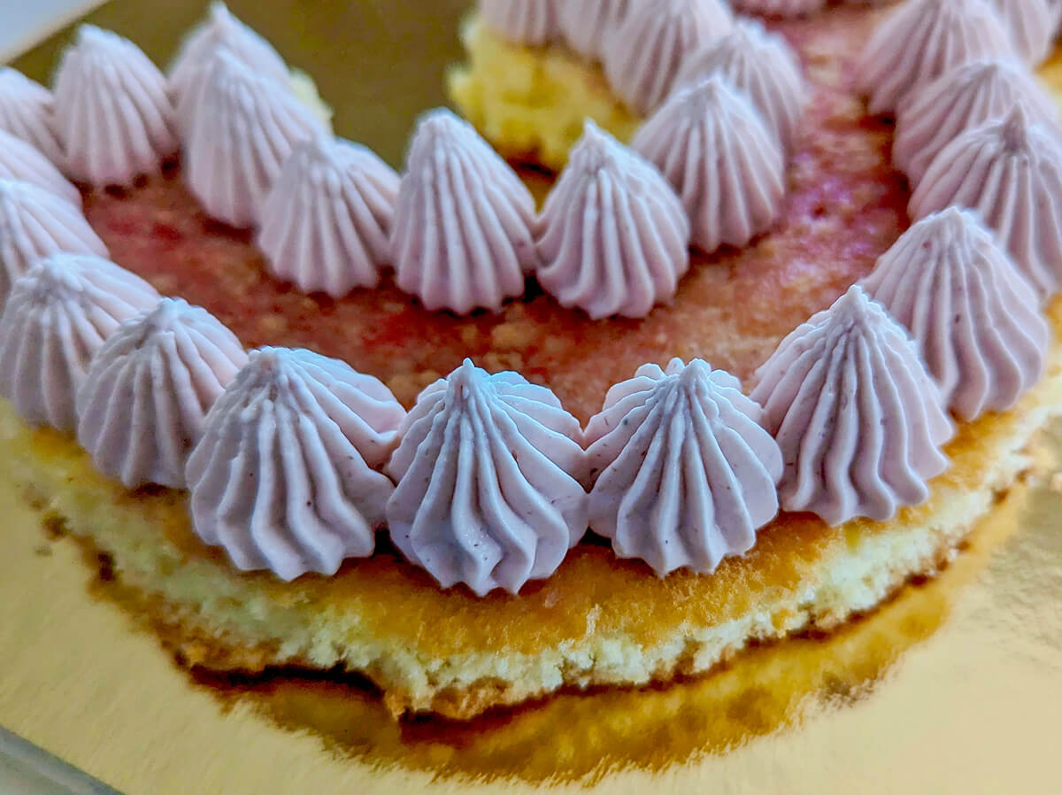 De la ganache framboise pochée sur un gâteau number cake.