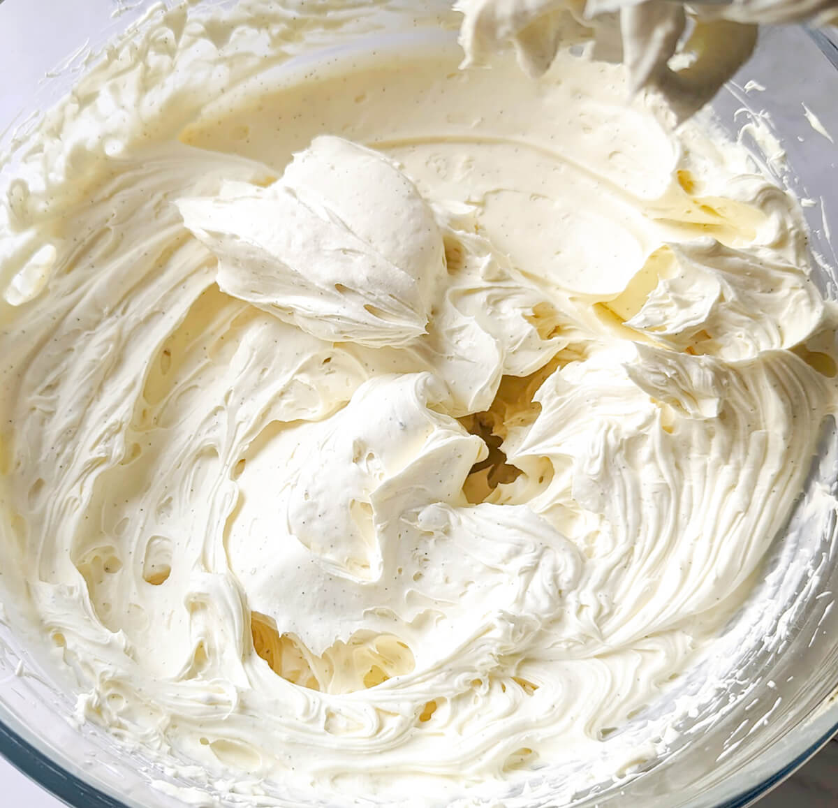 Gros plan sur une ganache montée à la vanille onctueuse et parsemée de grains de vanille noire.