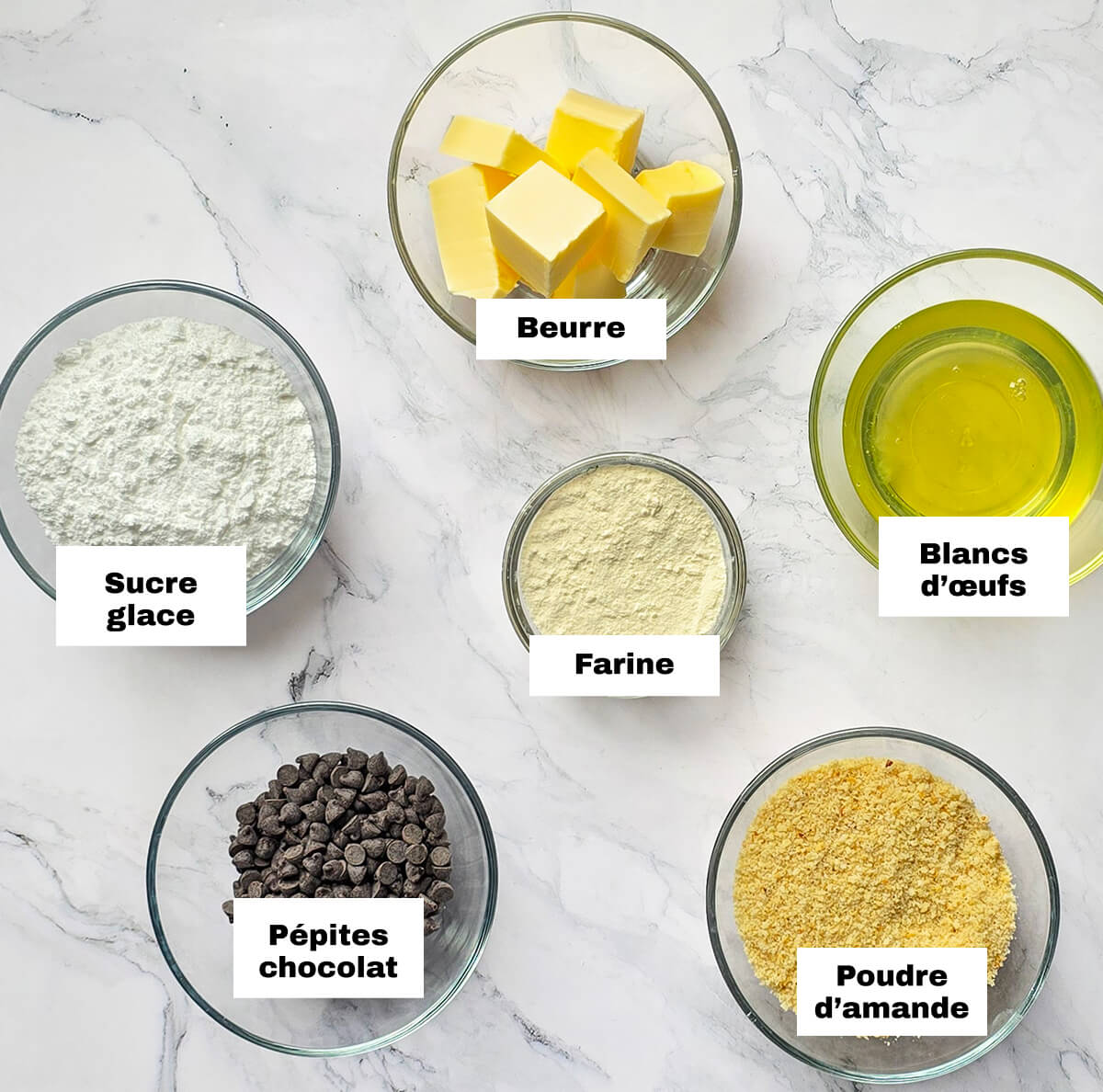 Ds ingrédients sur un fond blanc marbré pour faire une recette de tigrés au chocolat de Cyril Lignac.