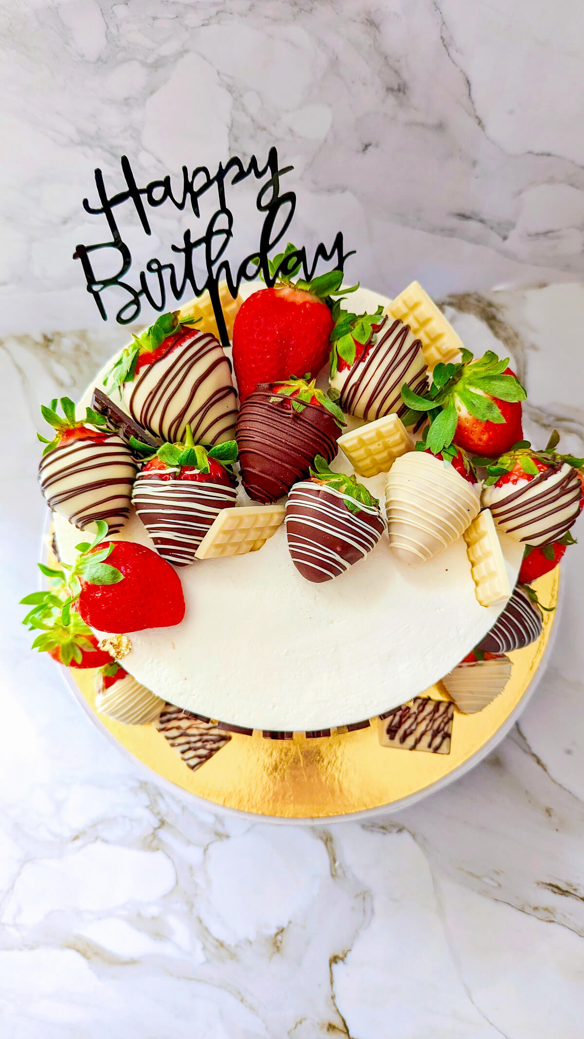 Un layer cake avec des fraises enrobées de chocolat sur le dessus.