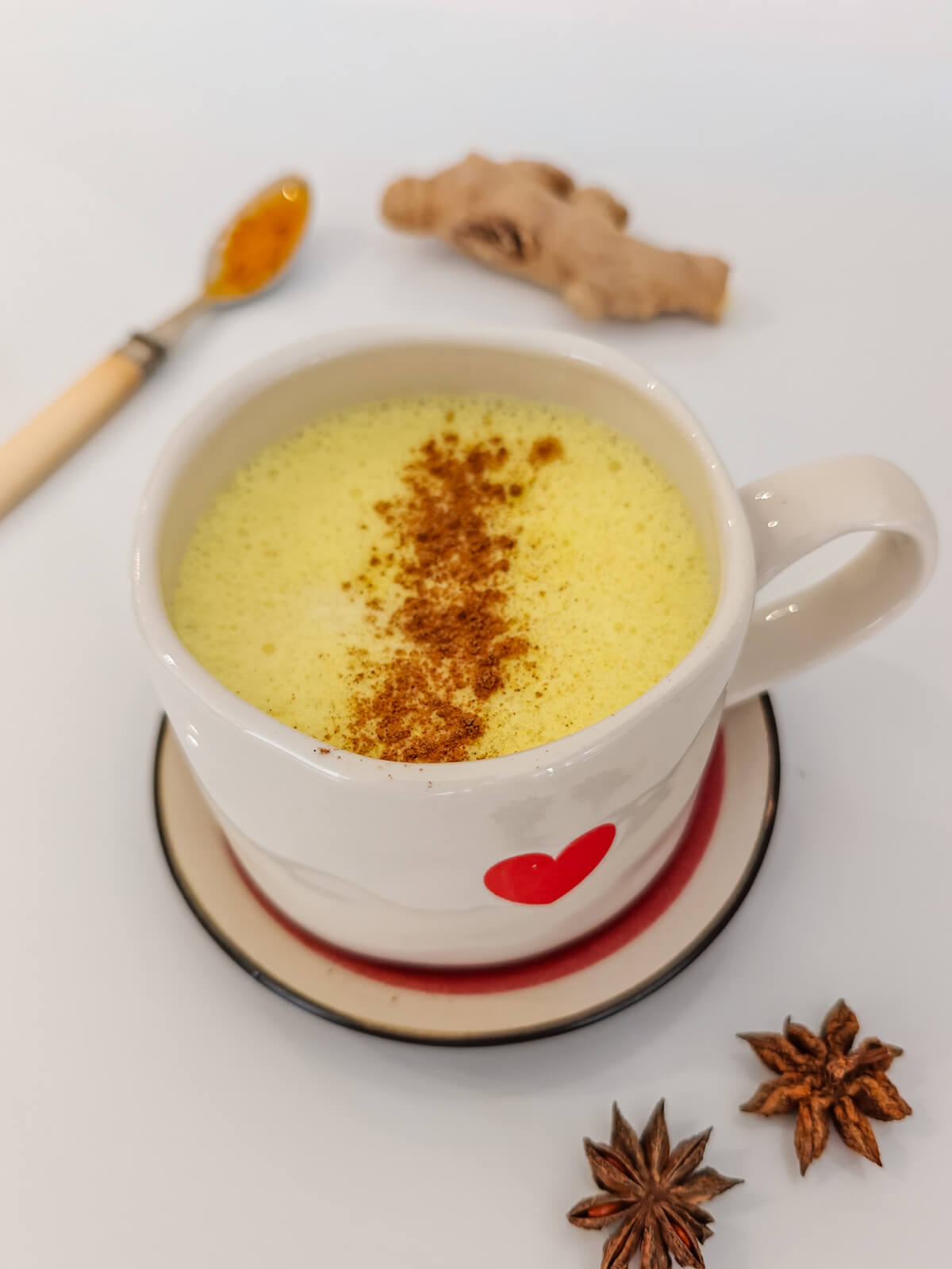 Un golden latte (ou lait d'or en francais) dans une tasse blanche, poudre de curcuma et gingembre dans le fond.