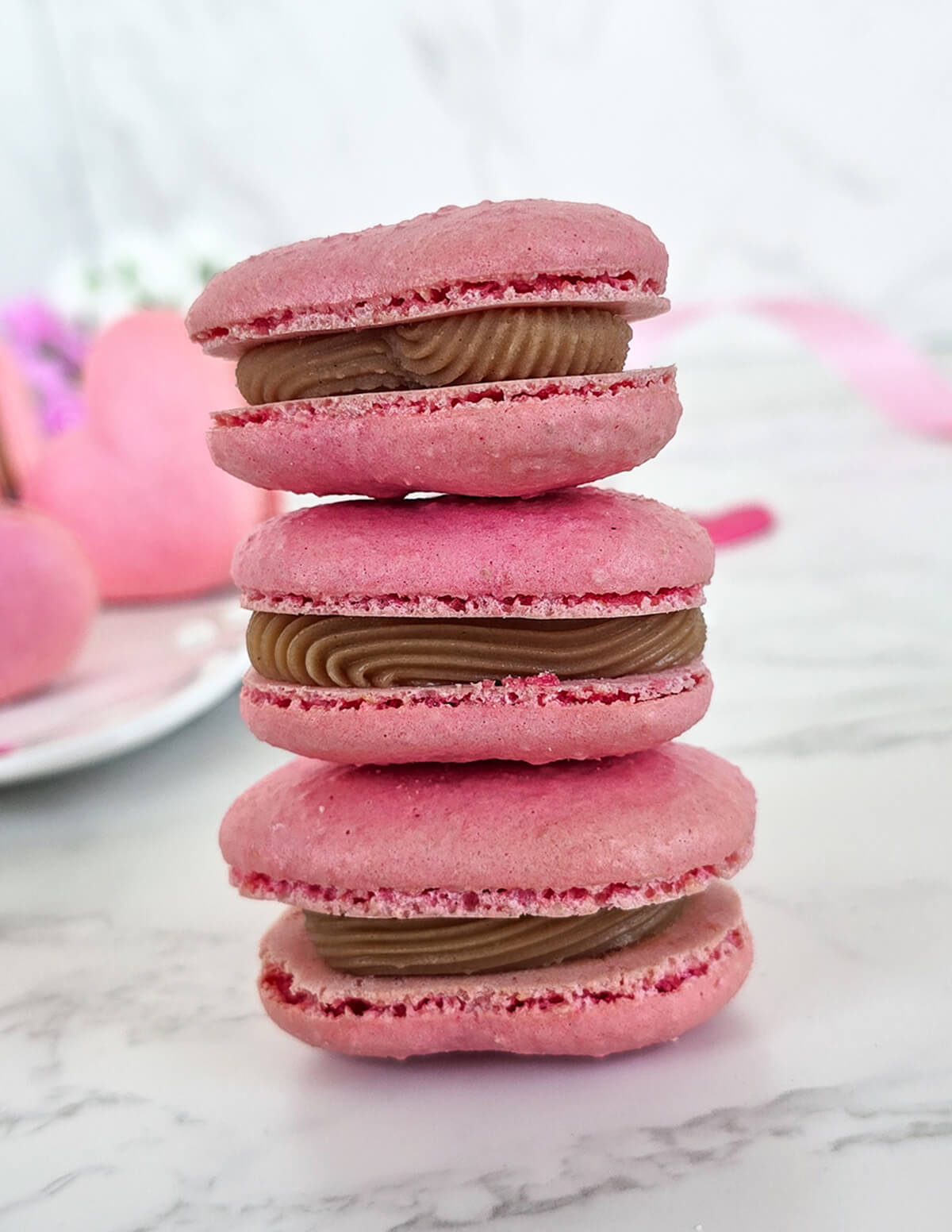 Des macarons coeur avec une ganache praliné empilés les uns sur les autres.