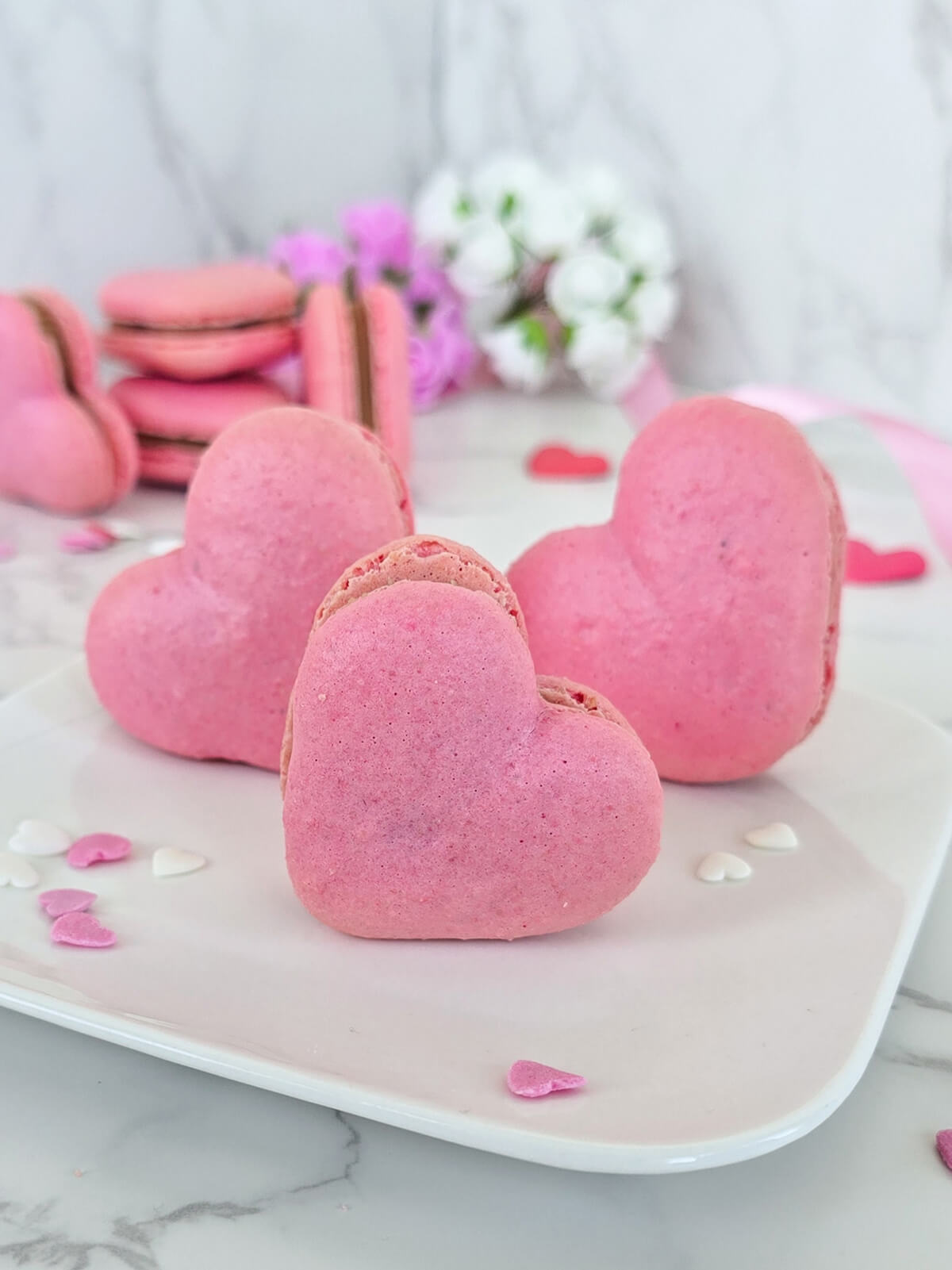 Des macarons en forme de cœur présentés dans une assiette blanche, idéaux pour la Saint-Valentin ou la Fête des Mères