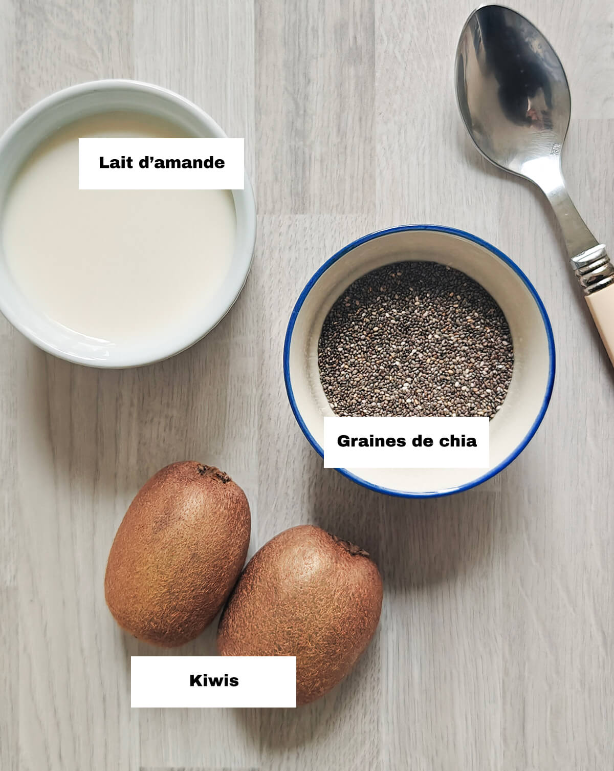 Les ingrédients d'un pudding chia kiwi sur un fond en bois clair.