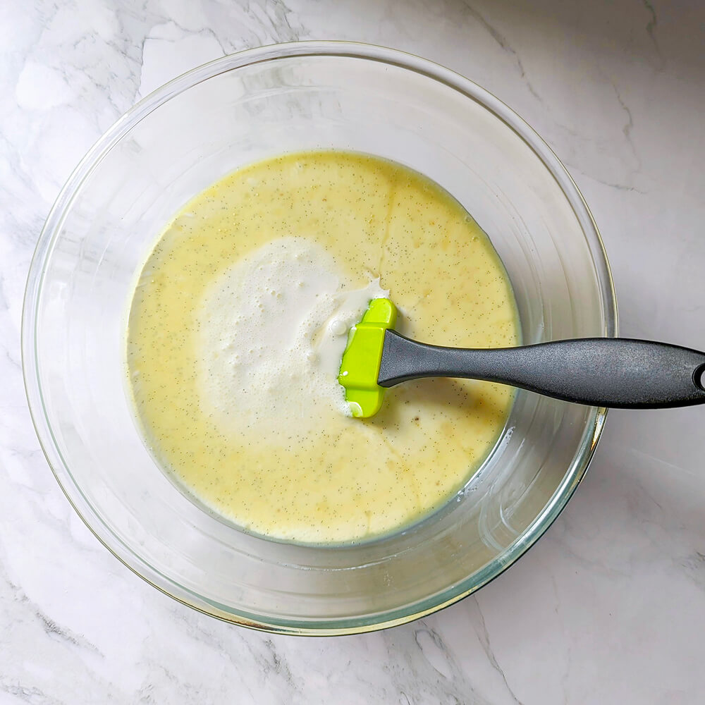 Incorporation de la crème liquide froide dans l'émulsion vanille et chocolat blanc pour stabiliser la ganache avant le repos au réfrigérateur.