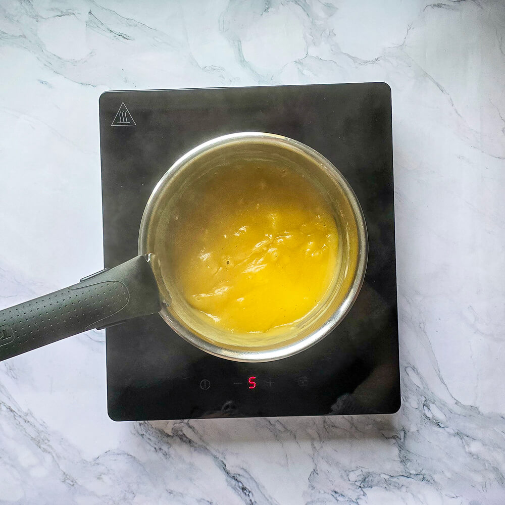 Faire bouillir de la purée de poire dans une casserole, sur un fond blanc marbré.
