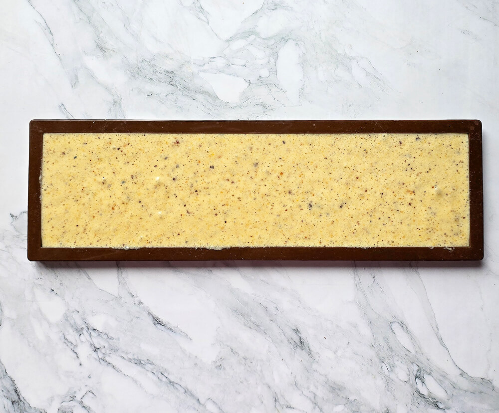 De la pâte à biscuit joconde dans un moule rectangulaire, avant cuisson.