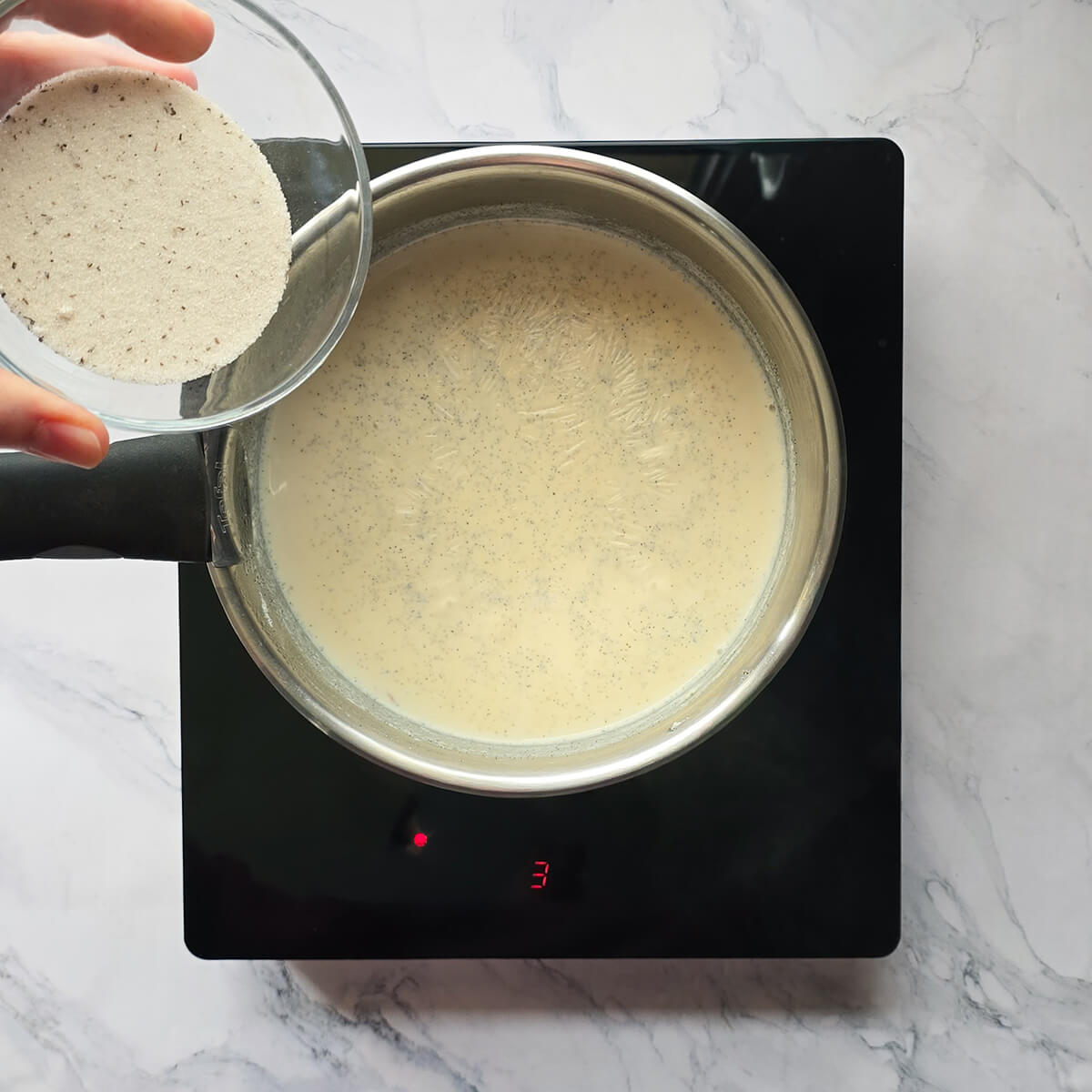 Ajout du sucre en fin de cuisson dans le riz au lait devenu crémeux et onctueux.