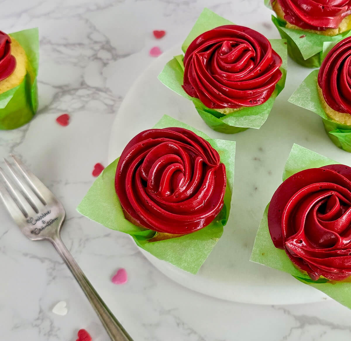 Des cupcakes rouges vifs en forme de rose pour la Saint-Valentin ou la fête des Mères, présentés sur une planche marbrée.