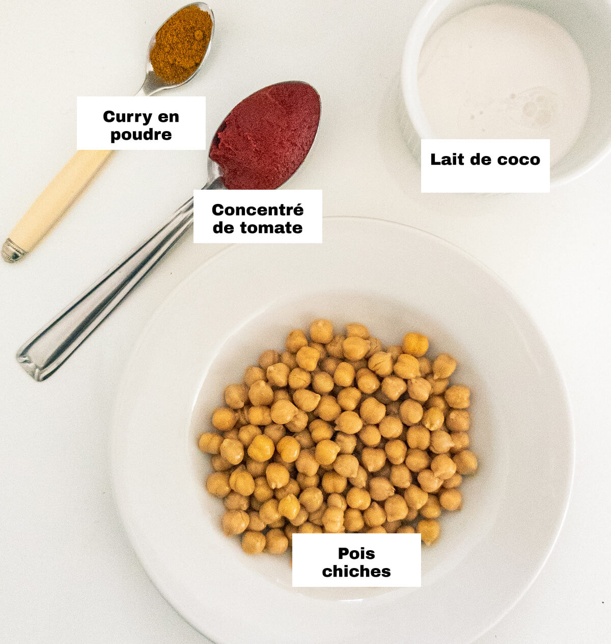 Des ingrédients pour réaliser un curry de pois chiches lait de coco, sur un fond blanc.
