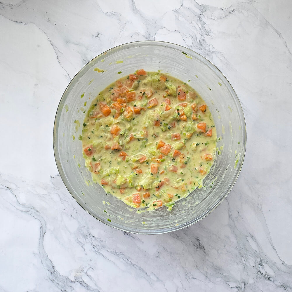 Mélange final dans un saladier associant les légumes cuits et la pâte pour former l'appareil à palets.
