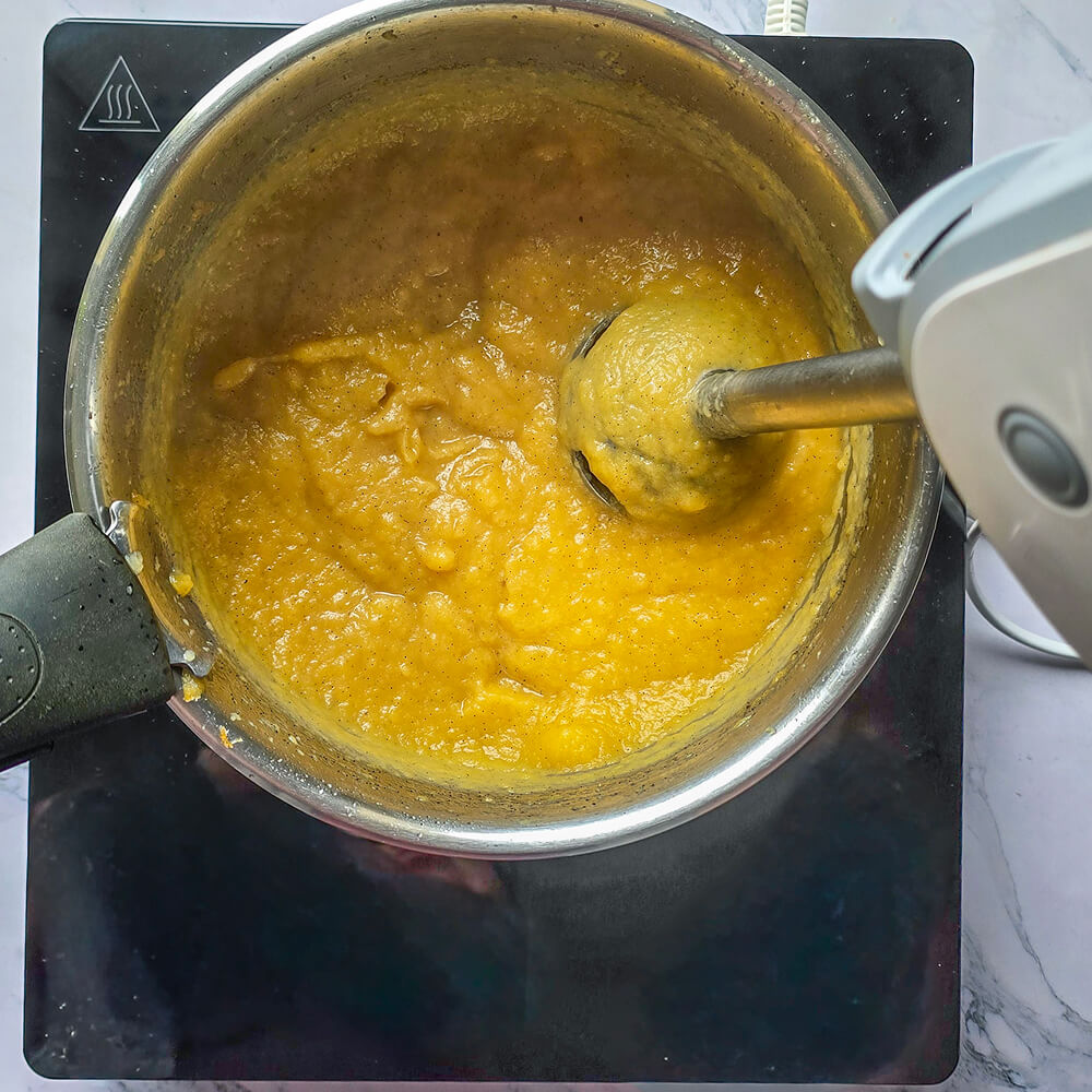 Un mixeur plongeant mettant en purée des pommes.