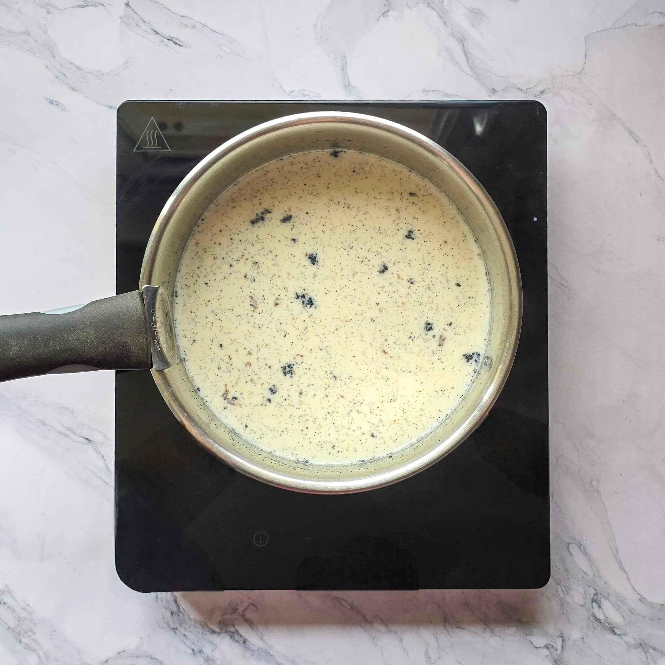 Chauffage du lait entier dans une casserole avec une gousse de vanille fendue et grattée.