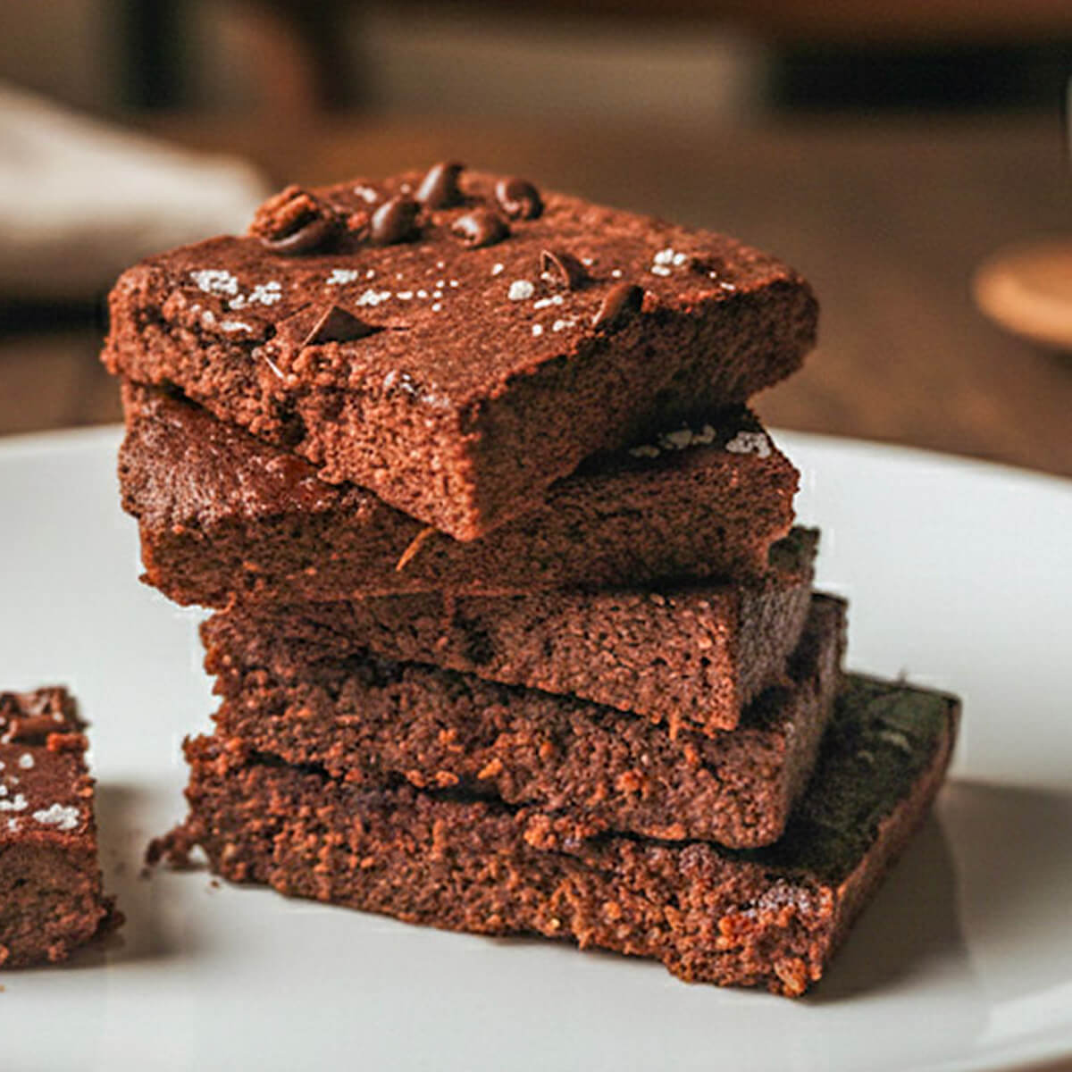 Des carrés de brownie patate douce dans une assiette blanche, sur une table en bois.