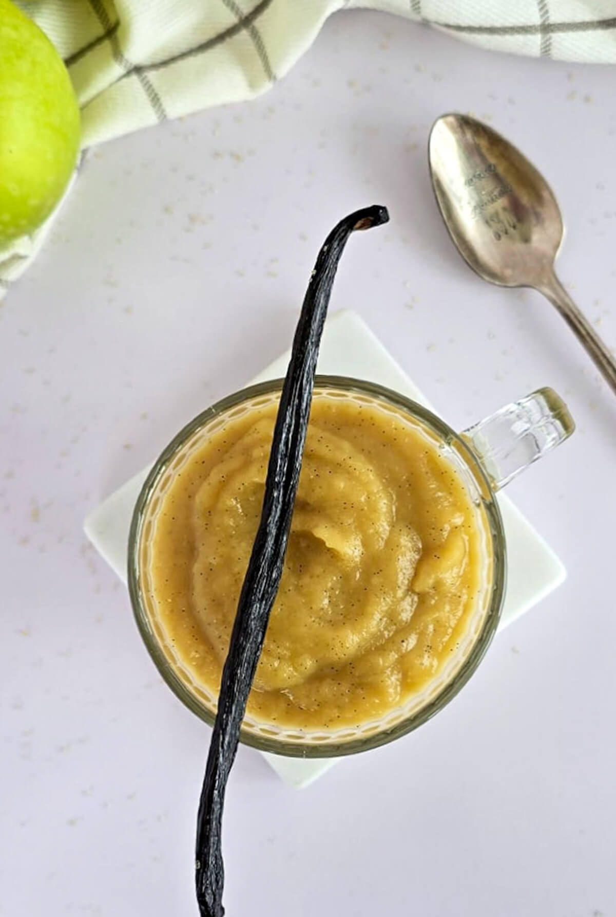De la compote de pommes à la vanille dans un verre à thé, gousse de vanille sur le dessus.