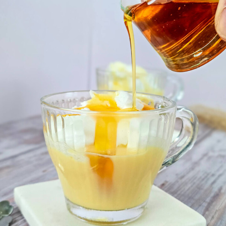 Main versant un caramel liquide ambré maison sur une île flottante aérienne, mettant en avant la texture gourmande du dessert express.