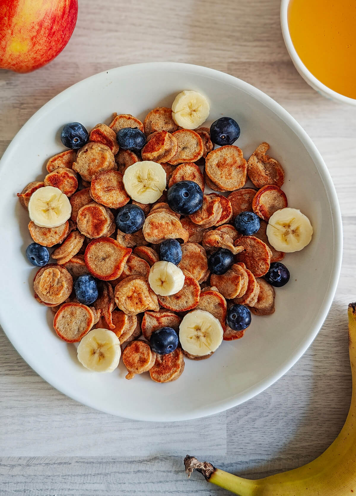 Des mini pancakes banane moelleux, dans une assiette avec des fruits.