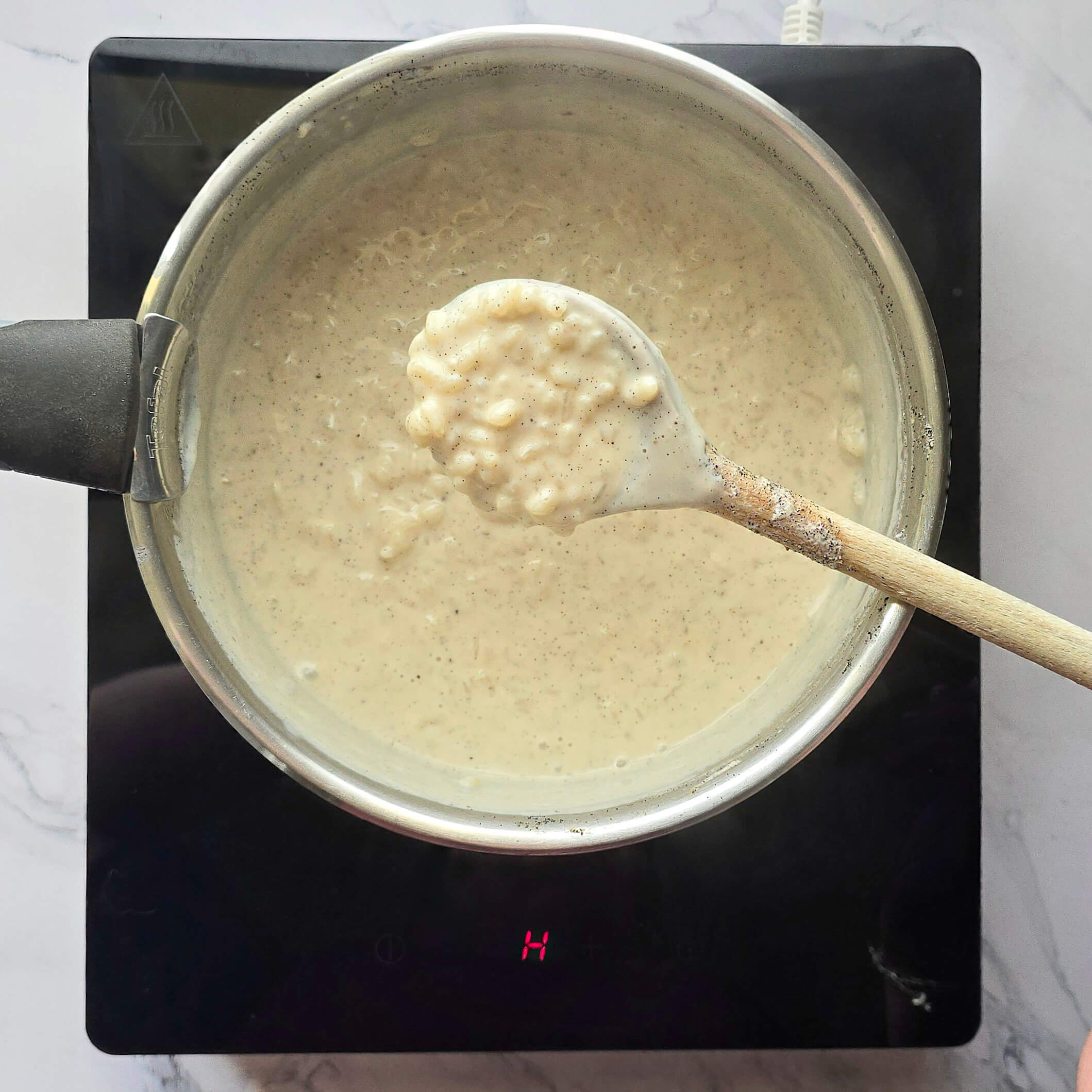 Riz au lait vanille crémeux qui nappe la cuillère dans une casserole.
