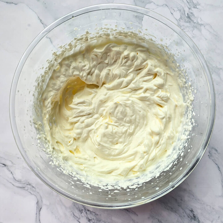 La texture d'une crème chantilly dans un saladier, sur un fond marbré.