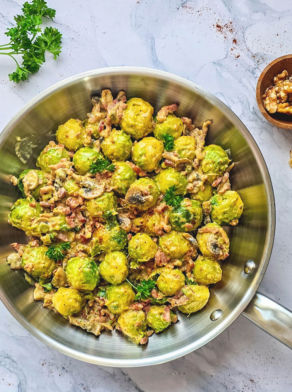 Une poêlée de choux de Bruxelles, lardons et champignons dans une poêle en inox.