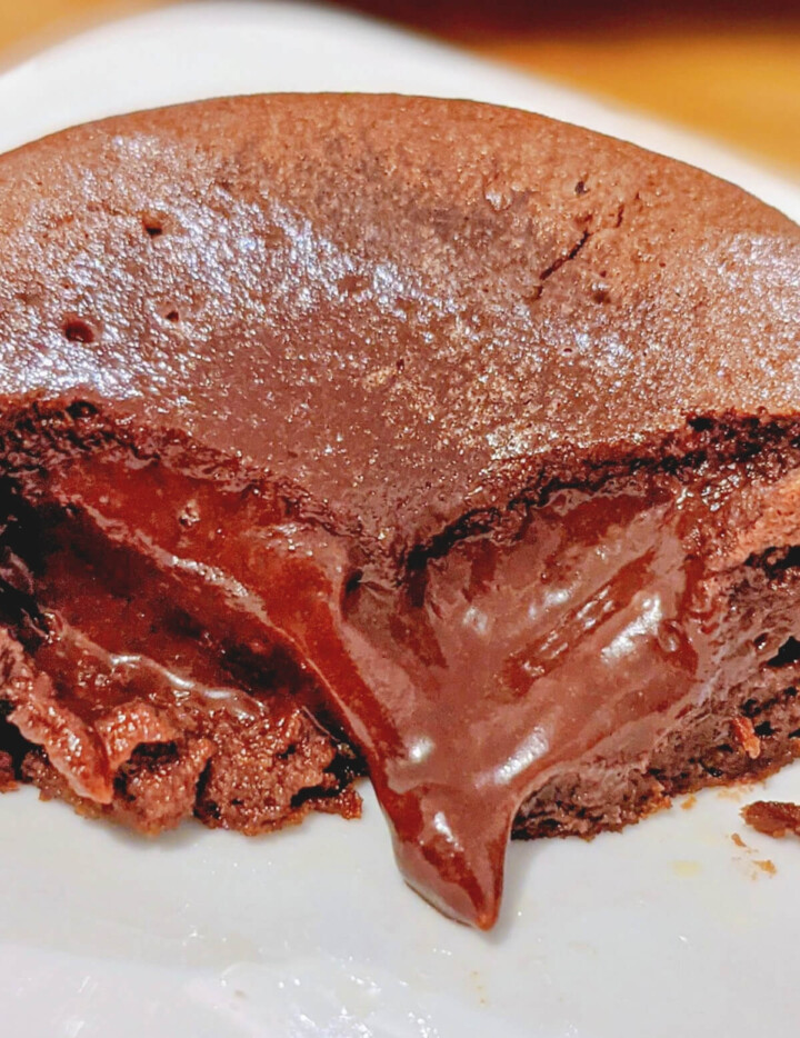 Un coeur coulant chocolat dans une assiette blanche, ouvert en deux.