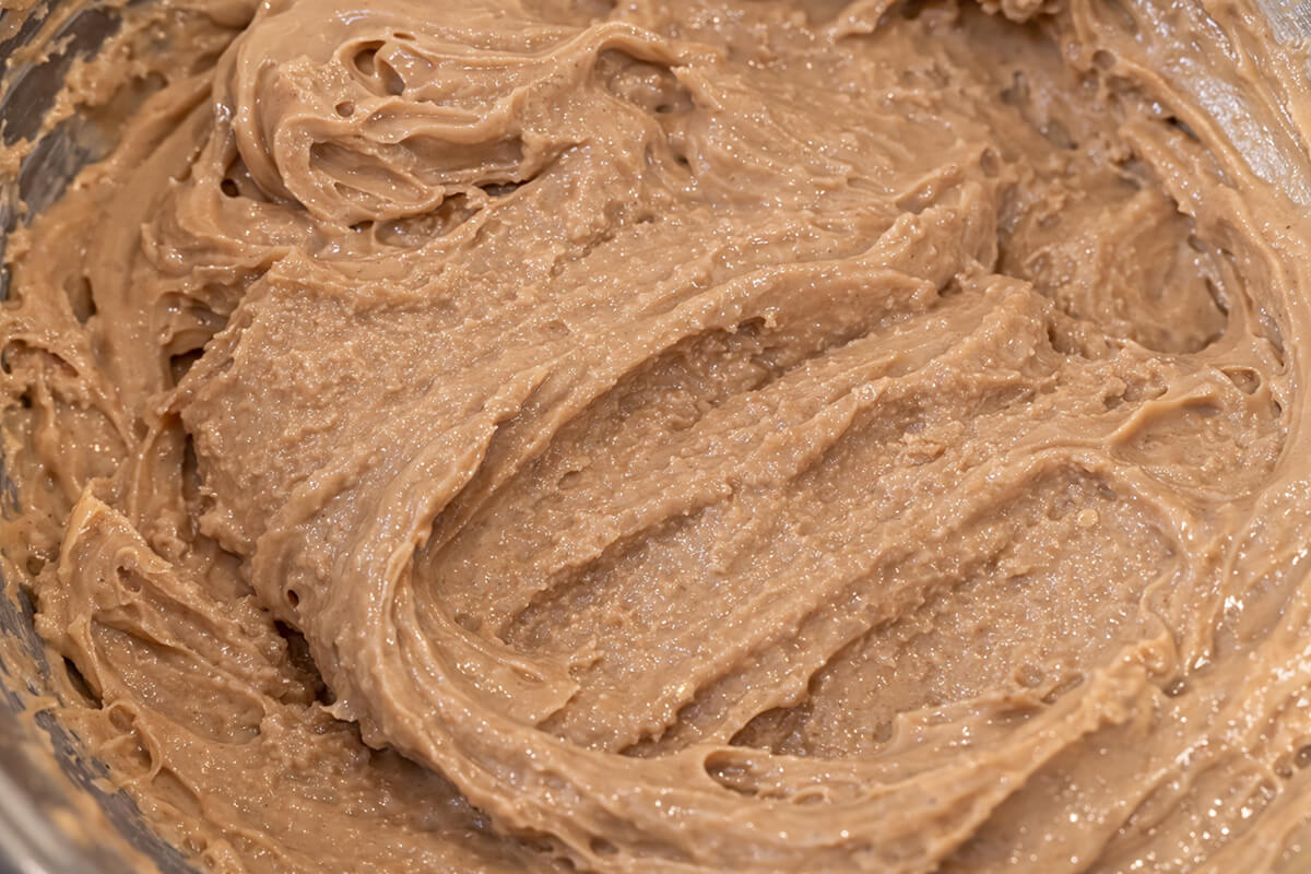 Gros plan d'une ganache au chocolat grainée et granuleuse dans un bol, présentant une texture sablonneuse et rugueuse au lieu d'être lisse, illustrant un chocolat qui a figé trop vite ou une mauvaise température.