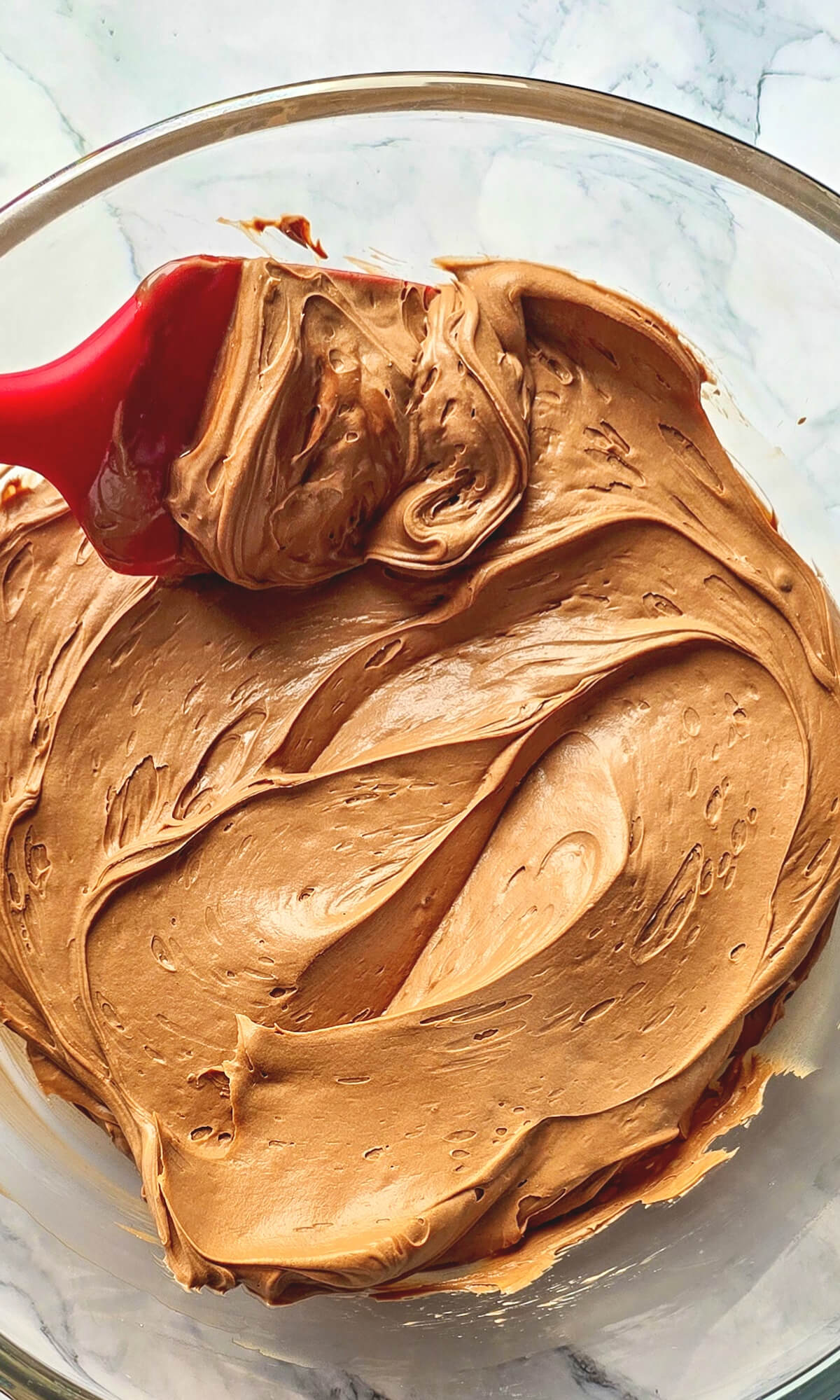 Ganache au Nutella crémeuse mélangée avec une spatule dans un bol, parfaite pour garnir un gâteau ou un layer cake.