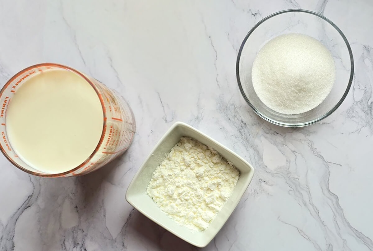 Des ingrédients pour réaliser des crèmes dessert, sur fond blanc marbré.