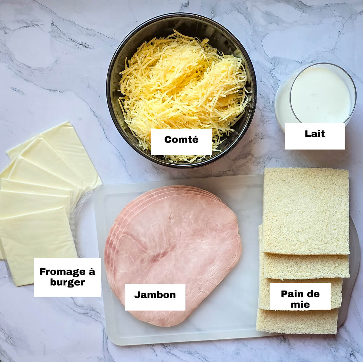 Des ingrédients pour faire des croques monsieur à l'airfryer, sur une surface blanc marbré.