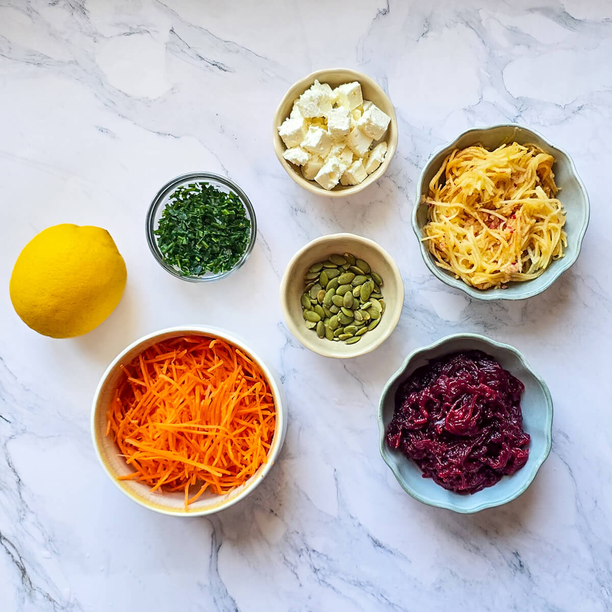 Des ingrédients pour faire une salade d'été betterave carotte et pomme, sur un fond blanc marbré.