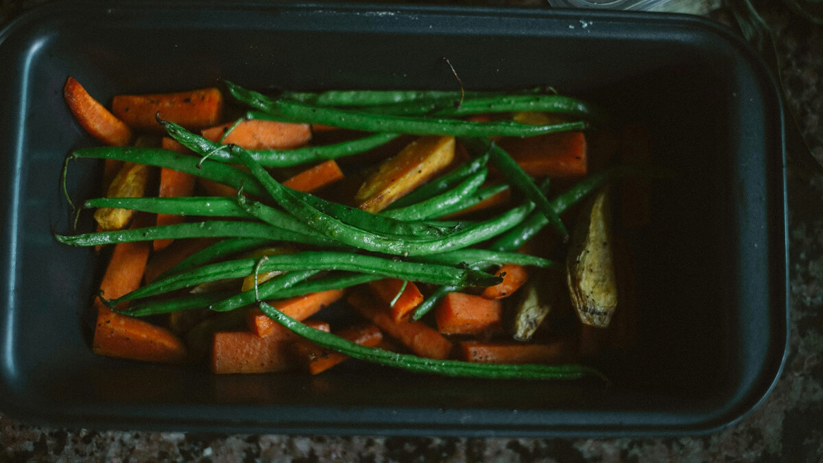 Des légumes rôtis dans la cuve d'un airfryer.